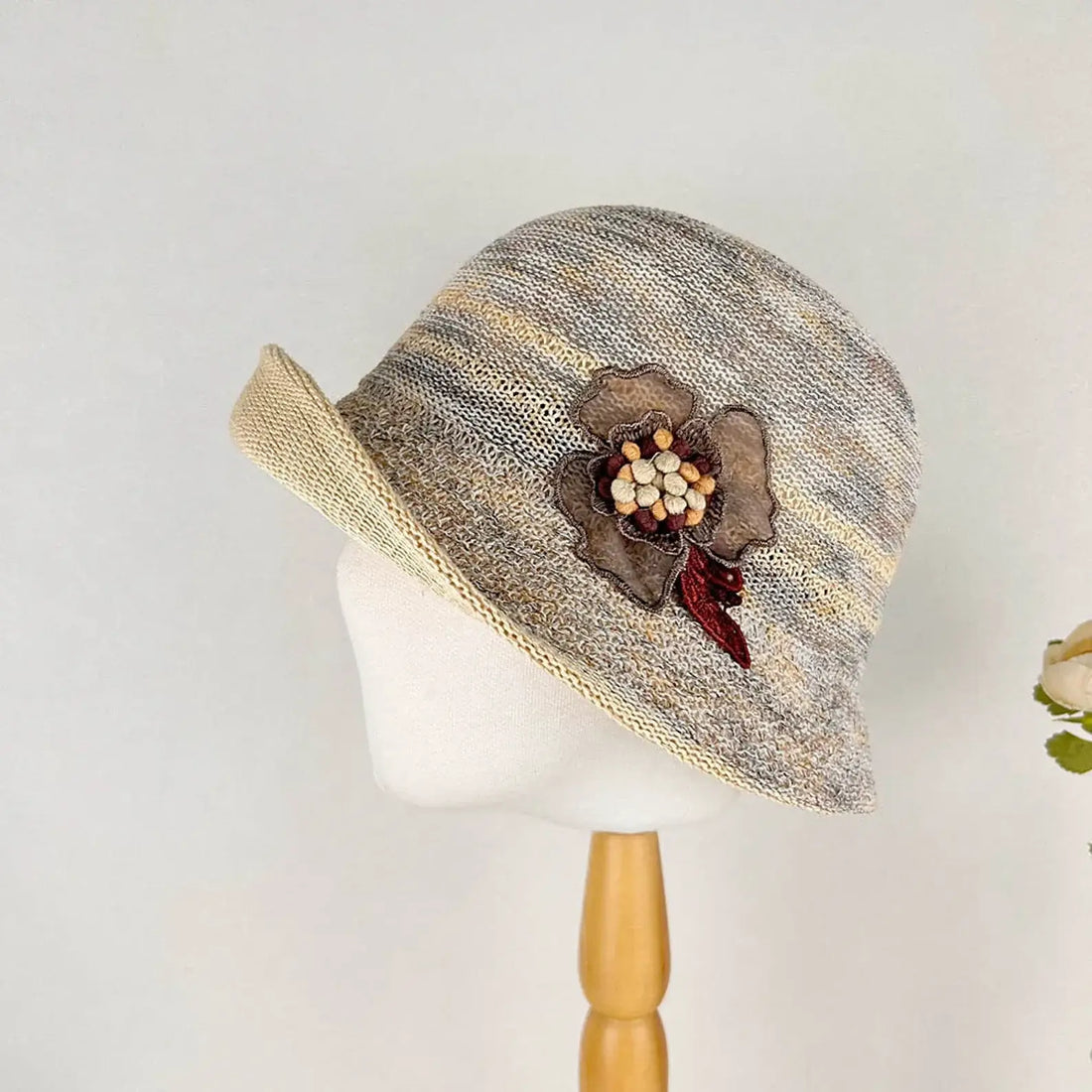 Floral crown knitted hat in neutral tones with a brown floral embellishment. A stylish and unique accessory.