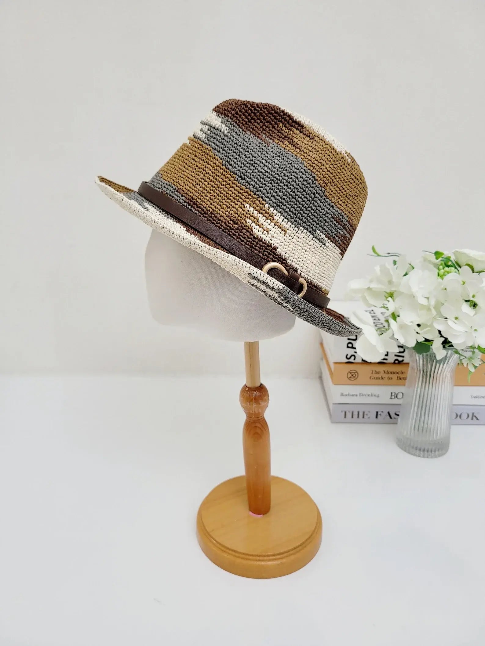 SERENGETI fedora hat: stylish striped pattern in brown, cream, and gray tones with a brown leather band and gold buckle, displayed on a mannequin head.