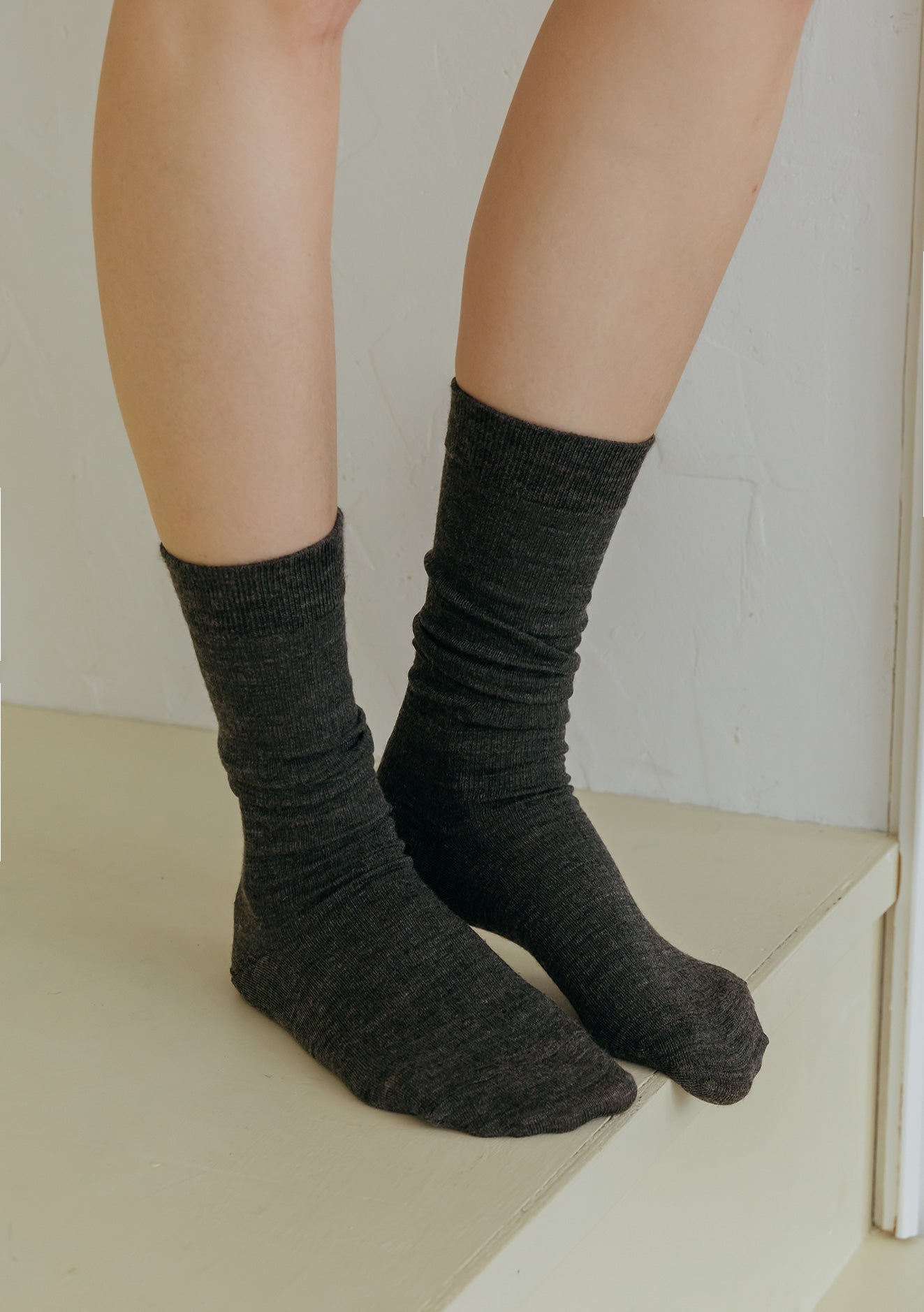 Person wearing dark gray socks on a light background