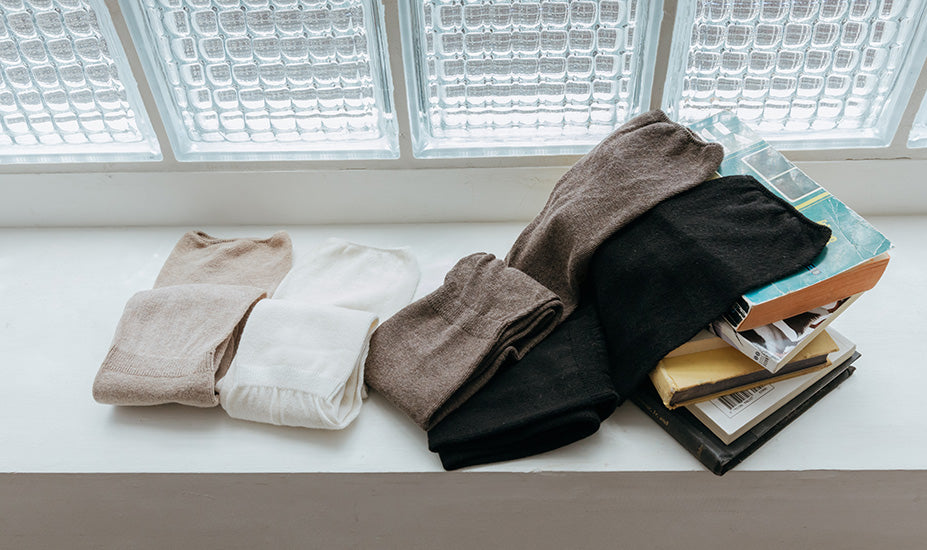 Folded clothes and books on a windowsill with glass blocks.