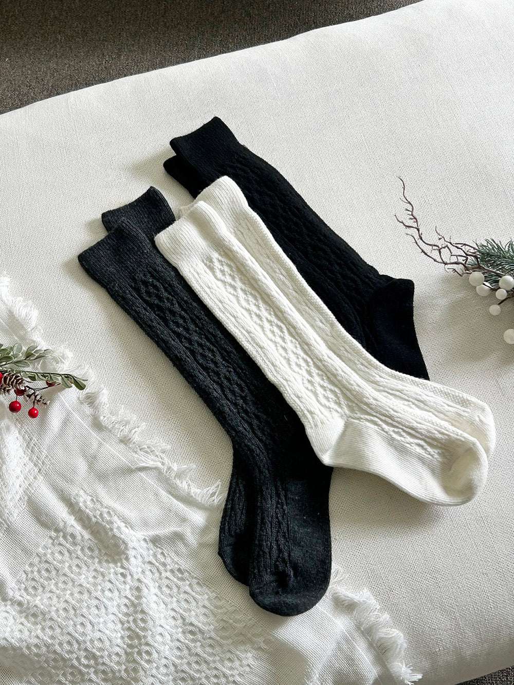 Pair of black and white knee-high socks on a textured surface with decorative elements.