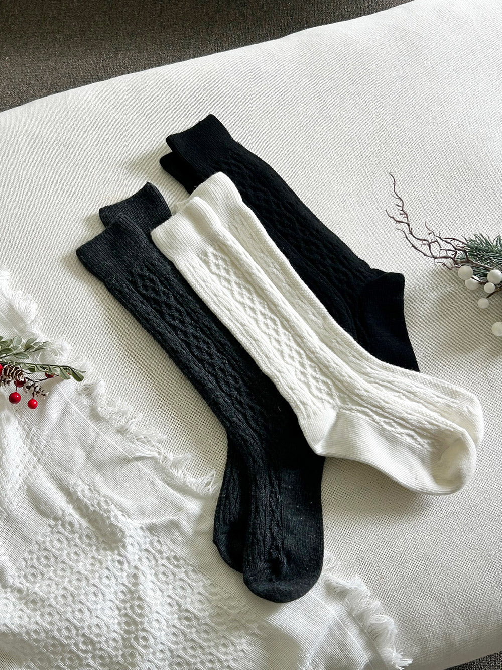Pair of black and white knee-high socks on a textured surface with decorative elements.