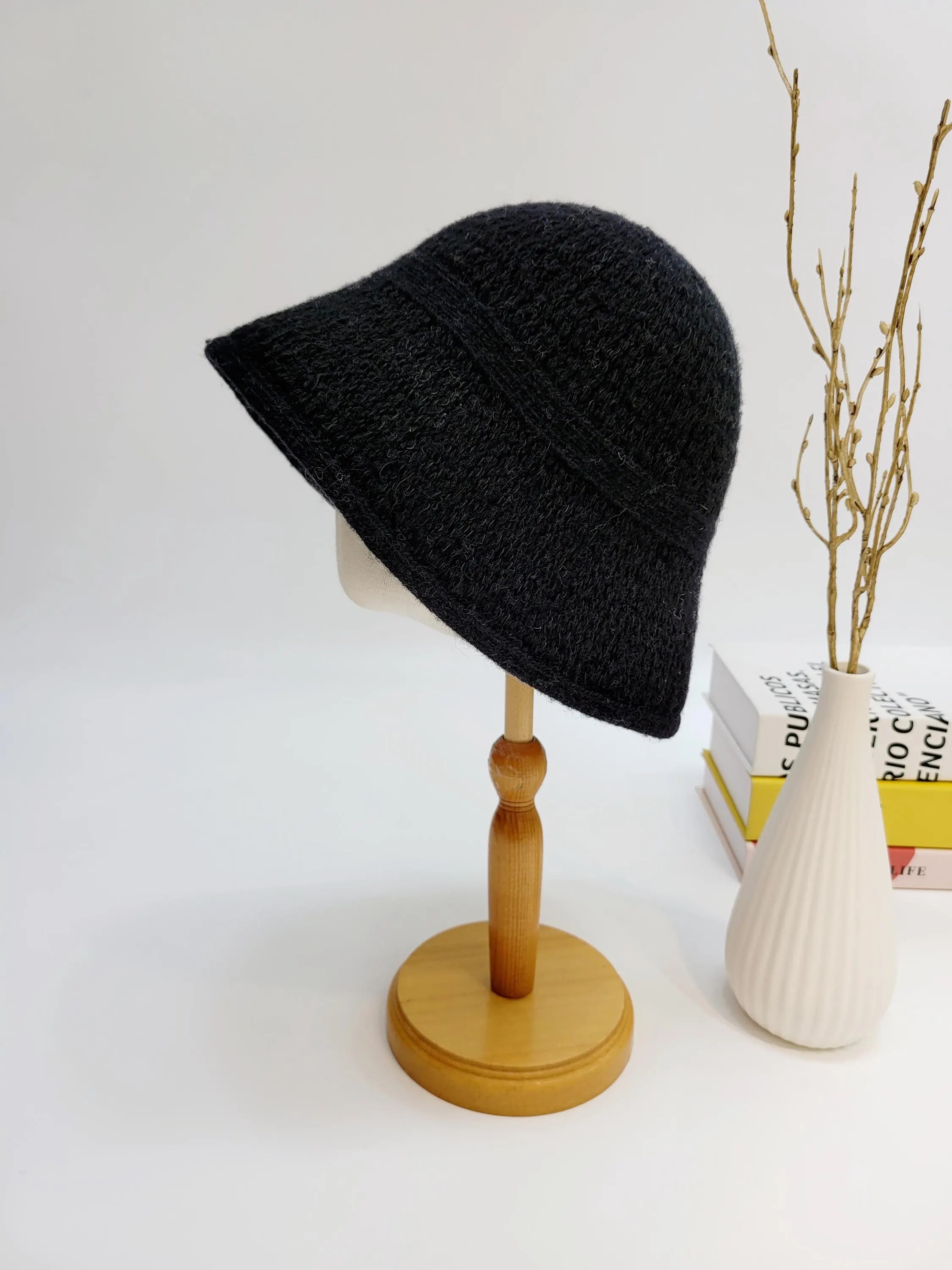 Black knit victoria's winter hat on a wooden stand. A cozy and stylish winter accessory.