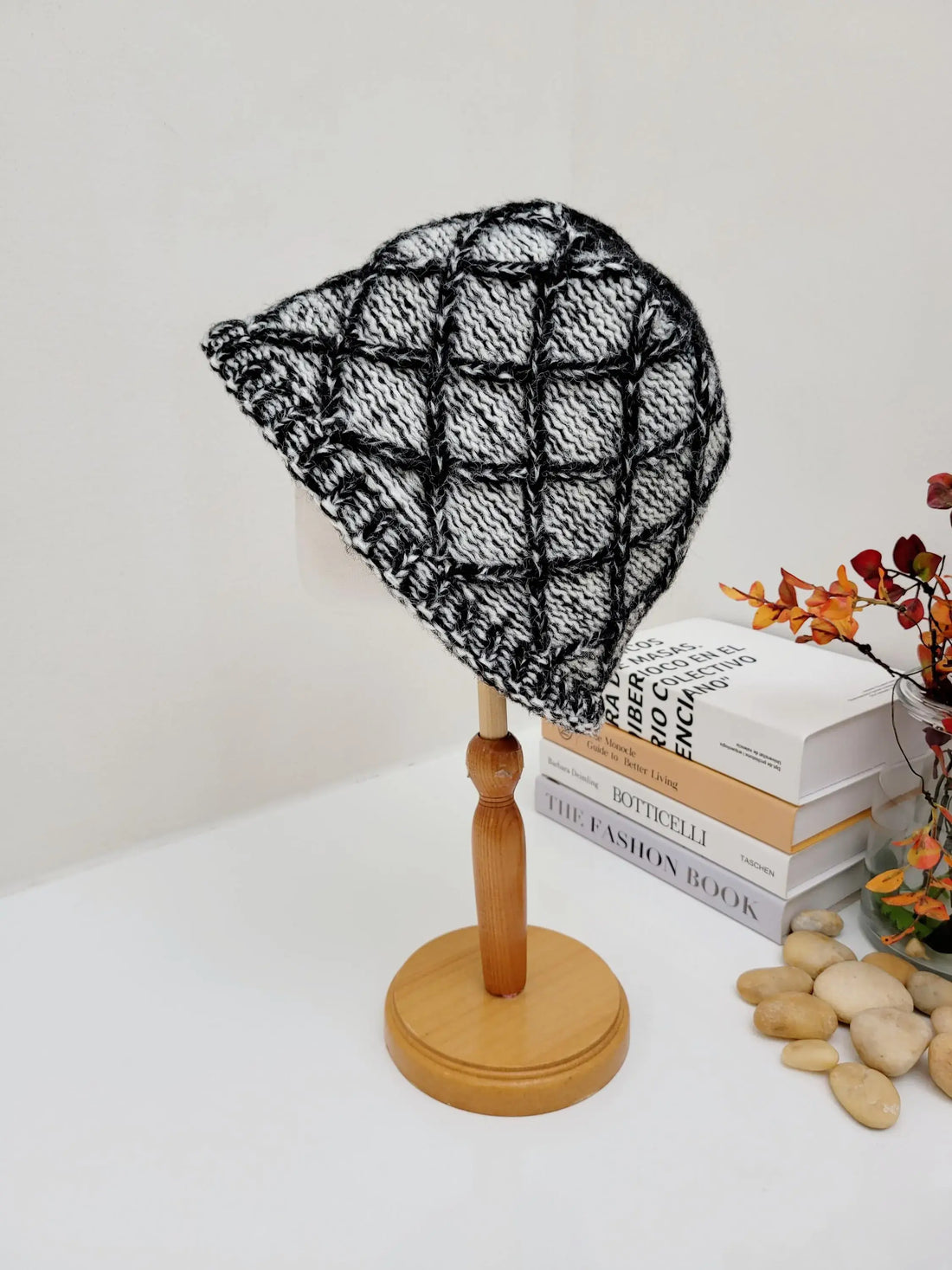 Black & white knit "winter in the paris" hat on a wooden stand. Features a textured, grid-like pattern.