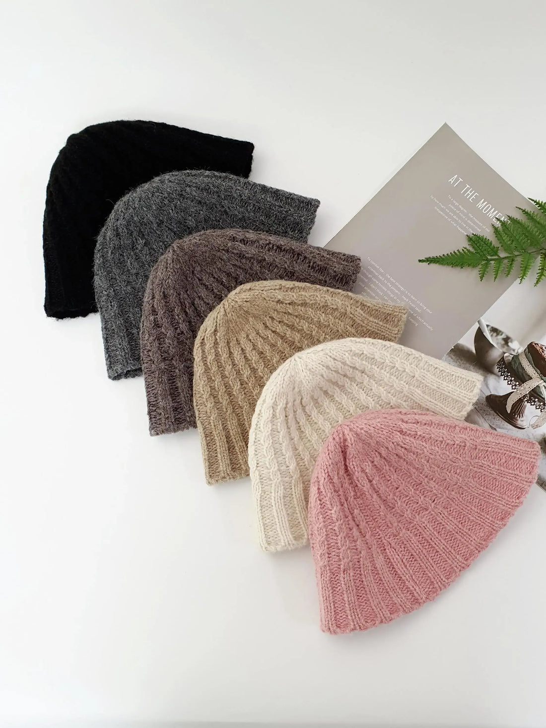 BEANIE THE WOOL-VOL3: Six knitted beanies in black, gray, brown, beige, off-white, and pink, showcasing a cozy and stylish winter headwear collection.