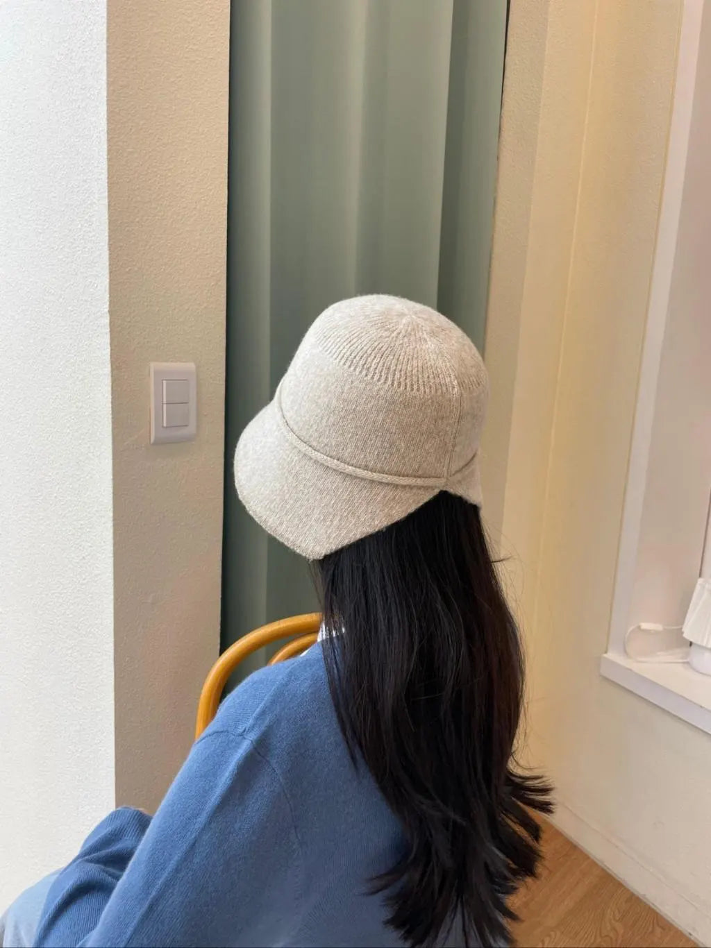 Beige knit bucket hat, the blair, paired with a blue sweater, seen from the back. Soft, cozy, and stylish.
