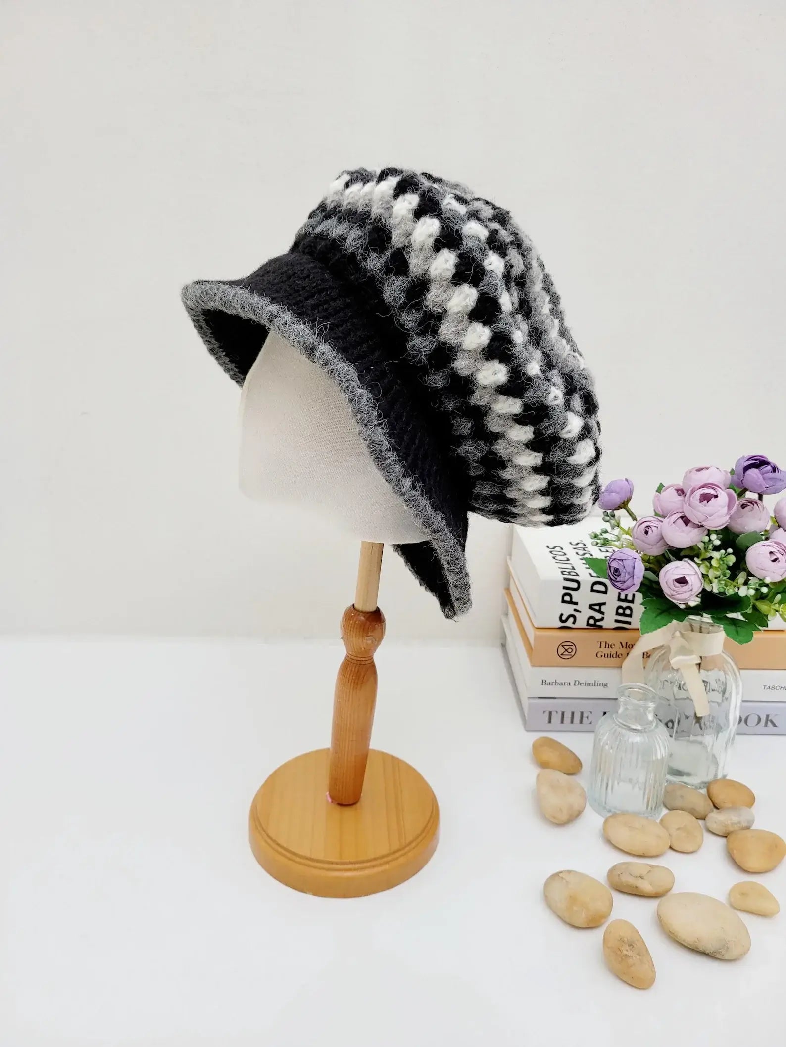 A collection of crocheted beret hats in various colors displayed on a wooden stand and table.