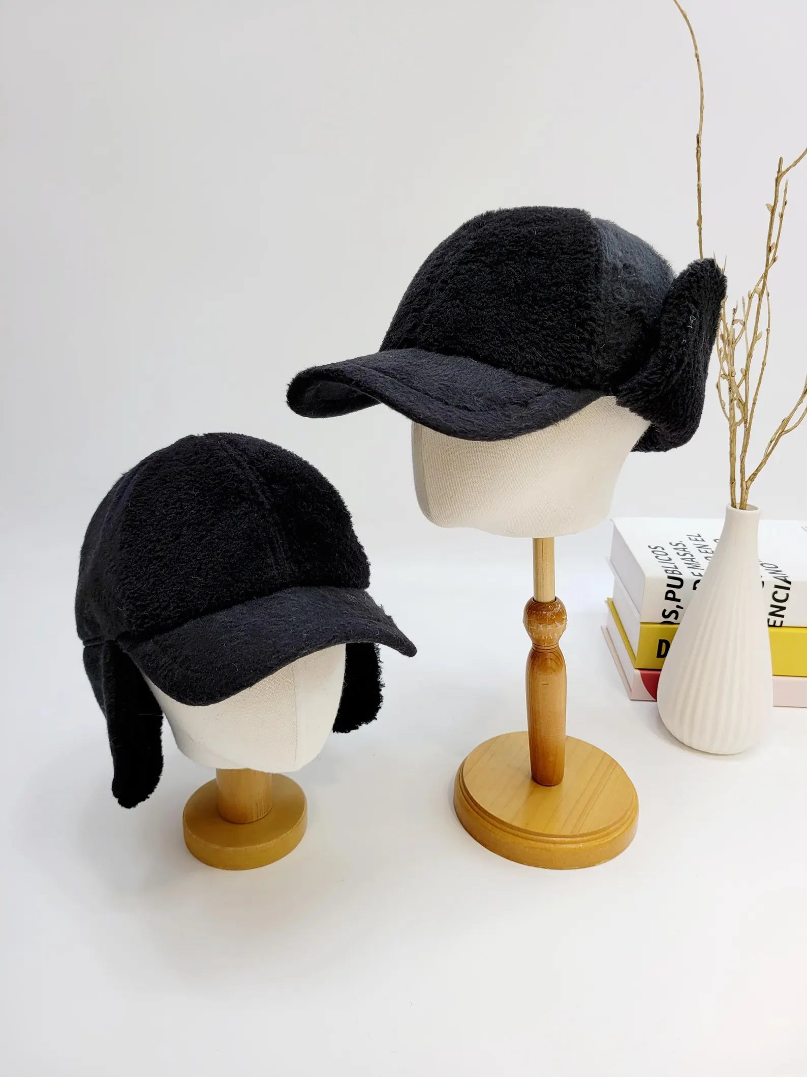 Two black jennifer on the street - winter hats with ear flaps on mannequin heads. Cozy, stylish winter headwear.