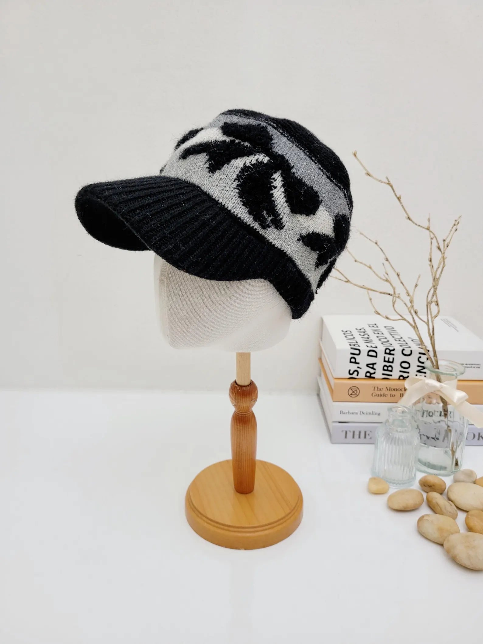 Black and gray knitted wool cap with visor, displayed on a mannequin head. This earmuff knitted wool cap offers warmth and style.