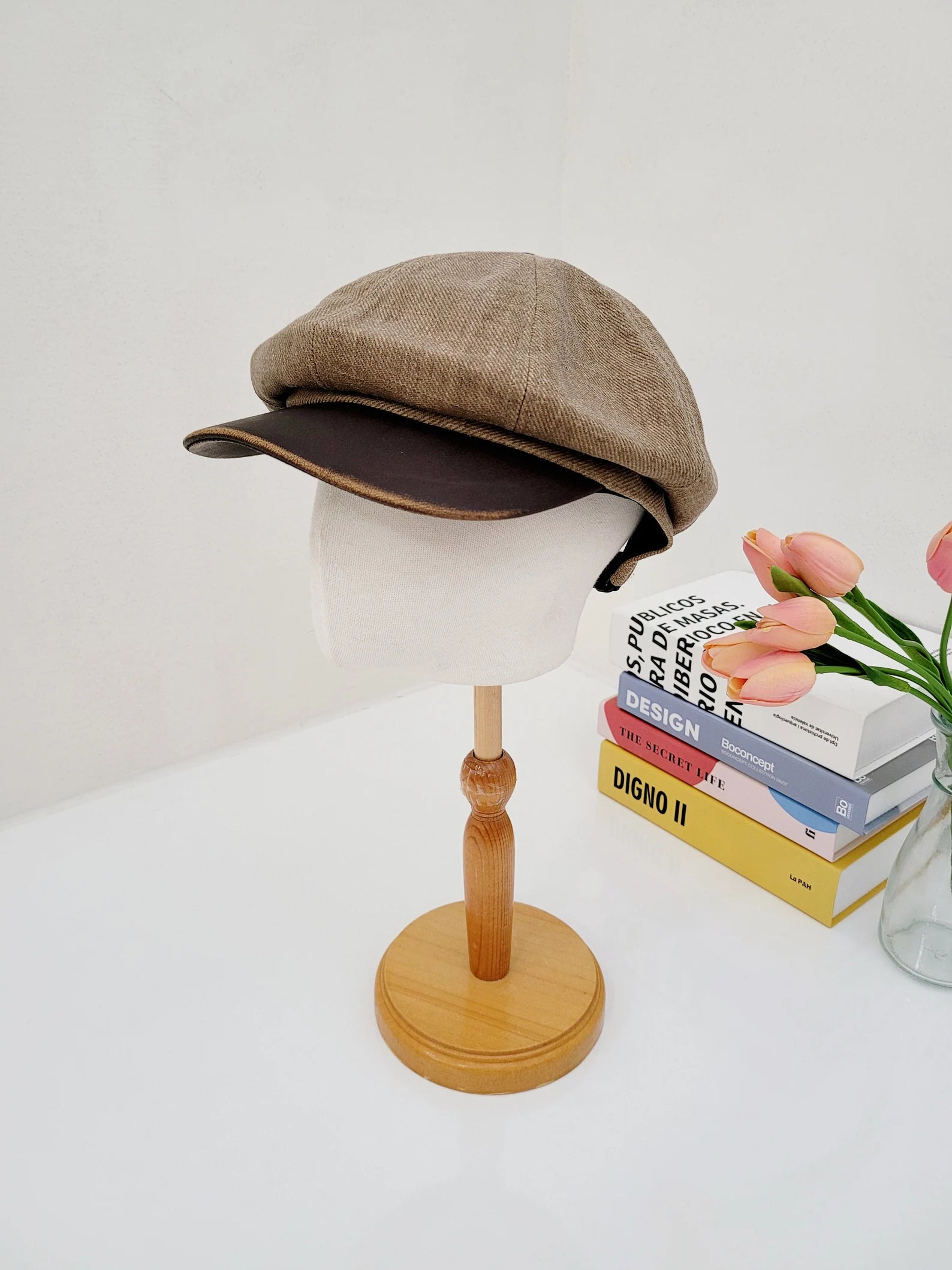 Brown tweed lana beret on a mannequin head, featuring a dark brown brim. Classic and stylish newsboy cap.