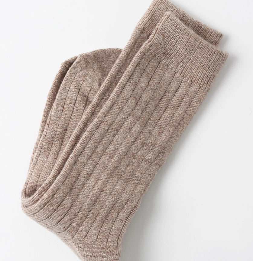 Folded beige ribbed socks on a white background