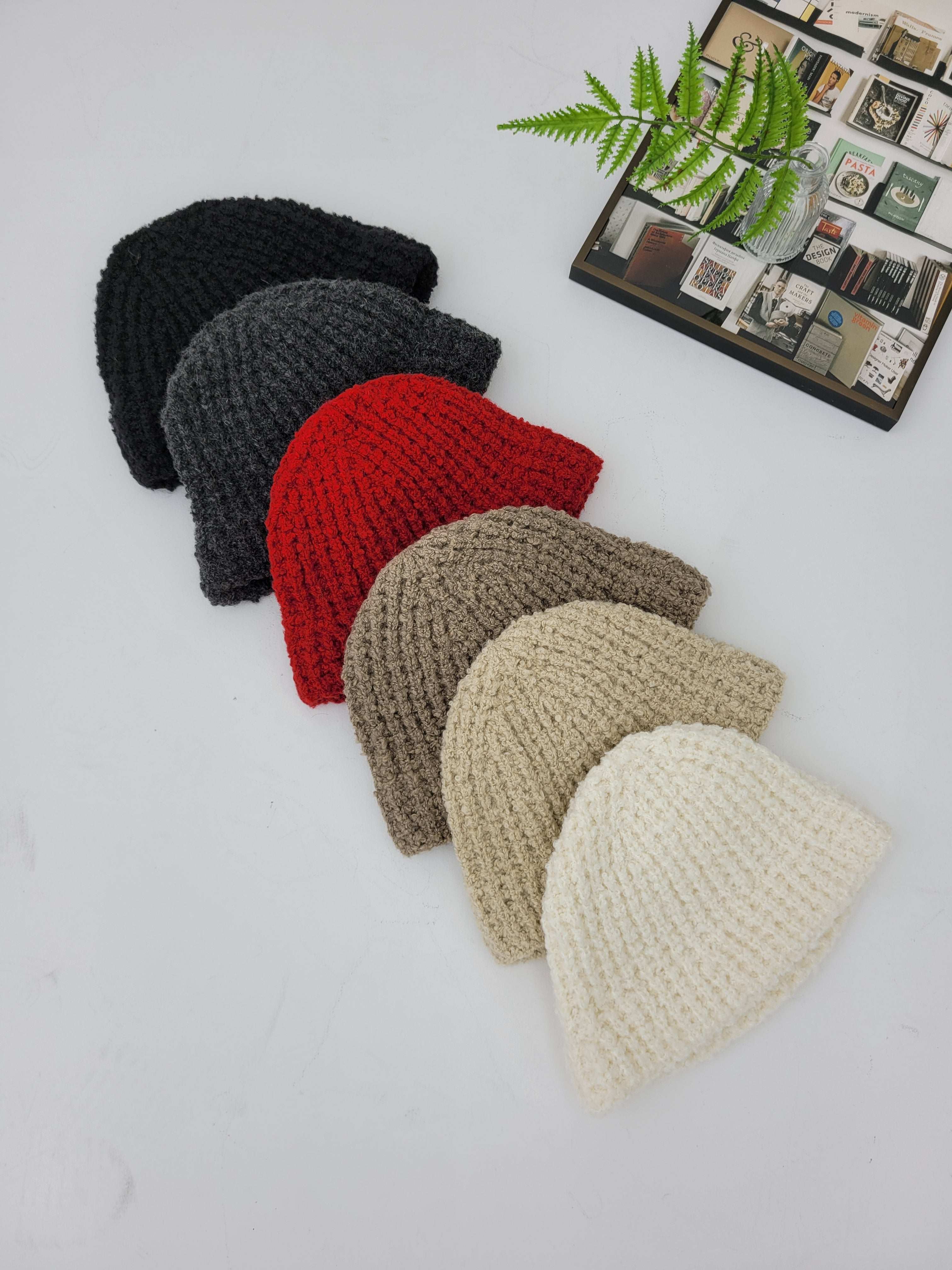 Set of six crocheted hats in black, red, gray, beige, and white on a light gray background.