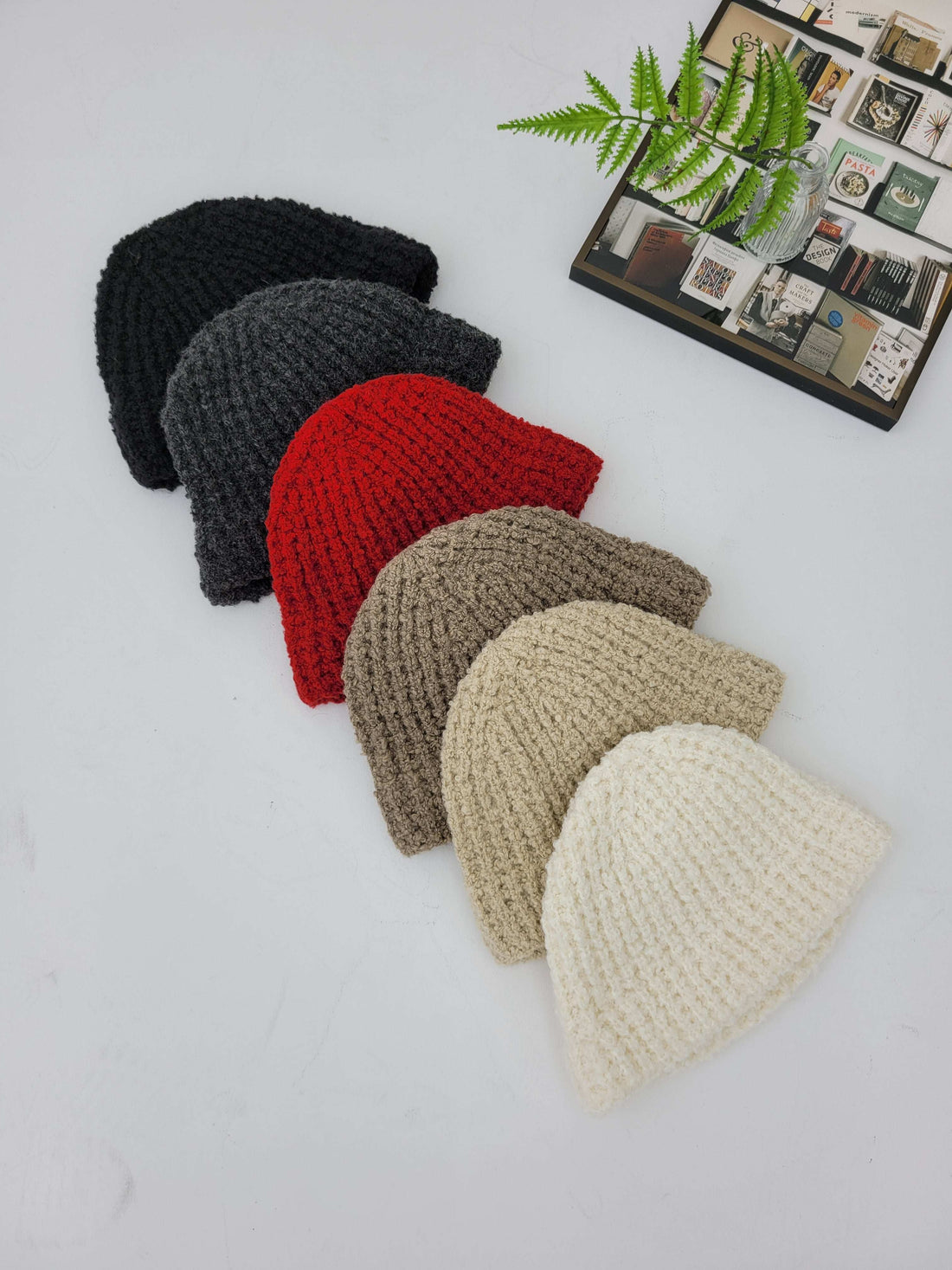 Set of six crocheted hats in black, red, gray, beige, and white on a light gray background.