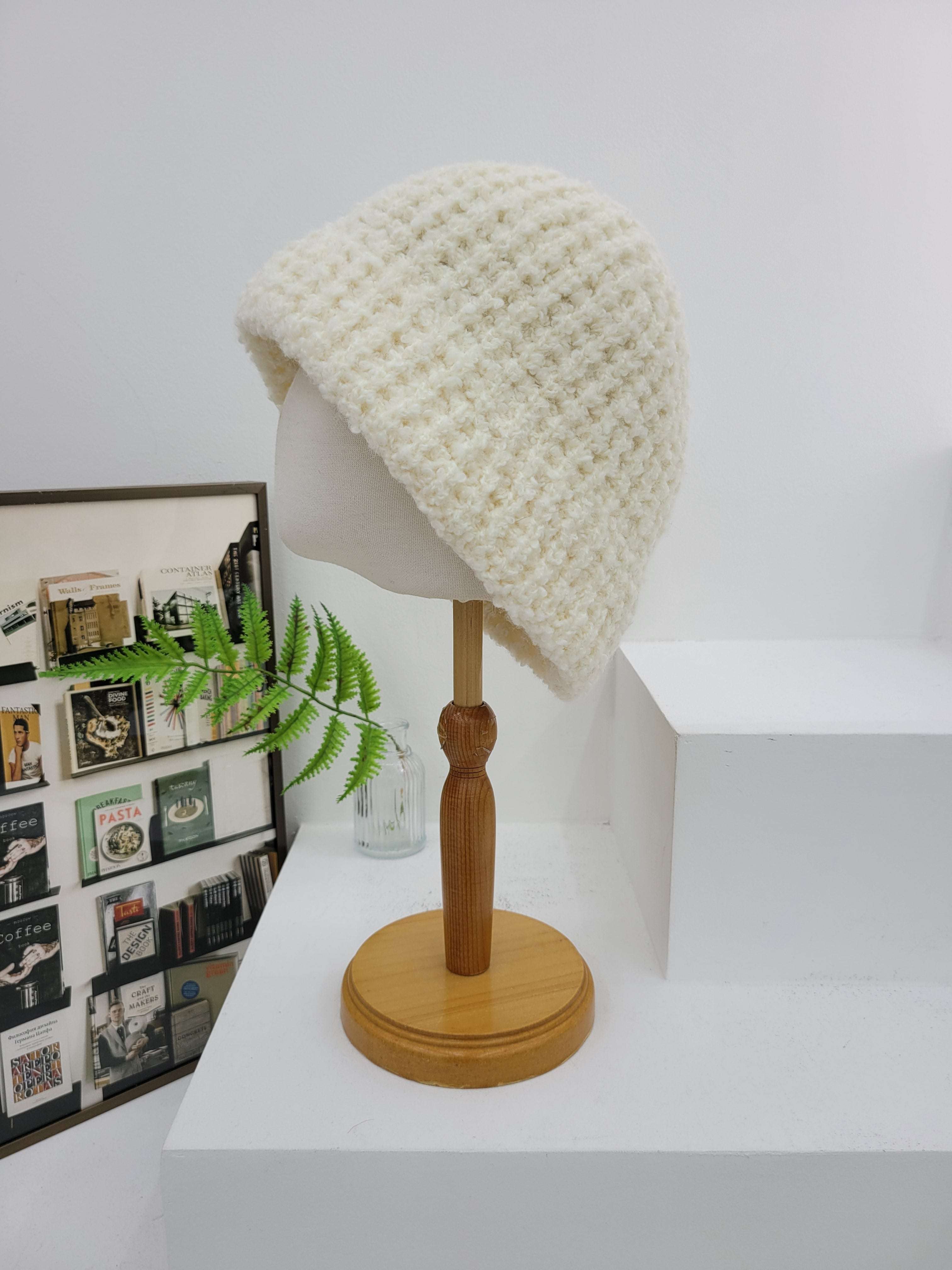 Wall-mounted lamp with a textured white shade and wooden base against a white wall.