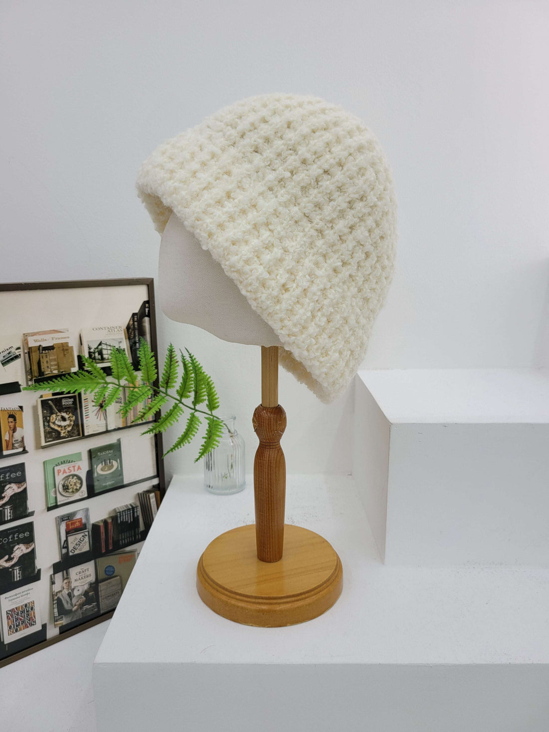 Wall-mounted lamp with a textured white shade and wooden base against a white wall.