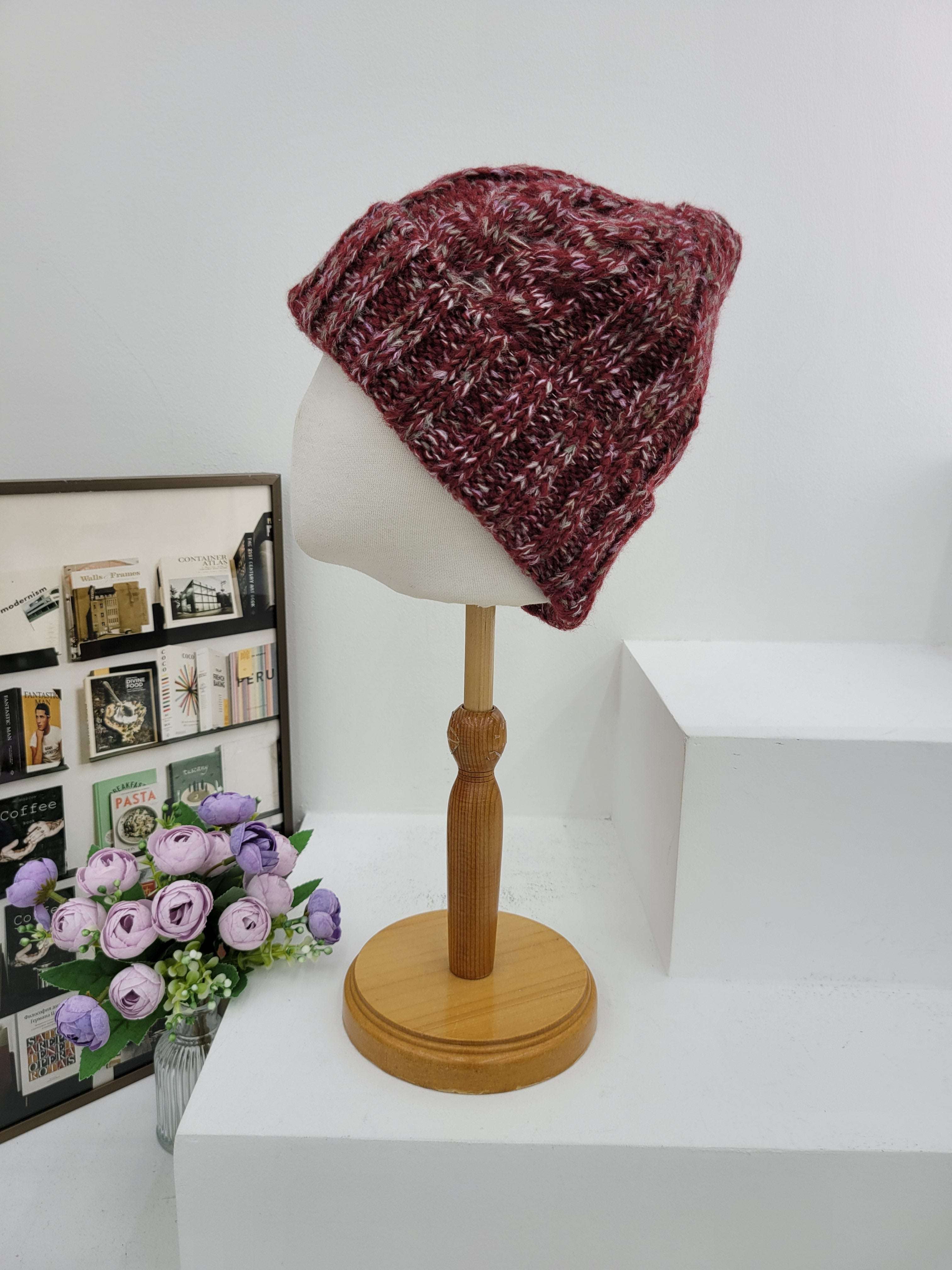 Knitted beanie on a mannequin head next to a wall lamp with a wooden base.