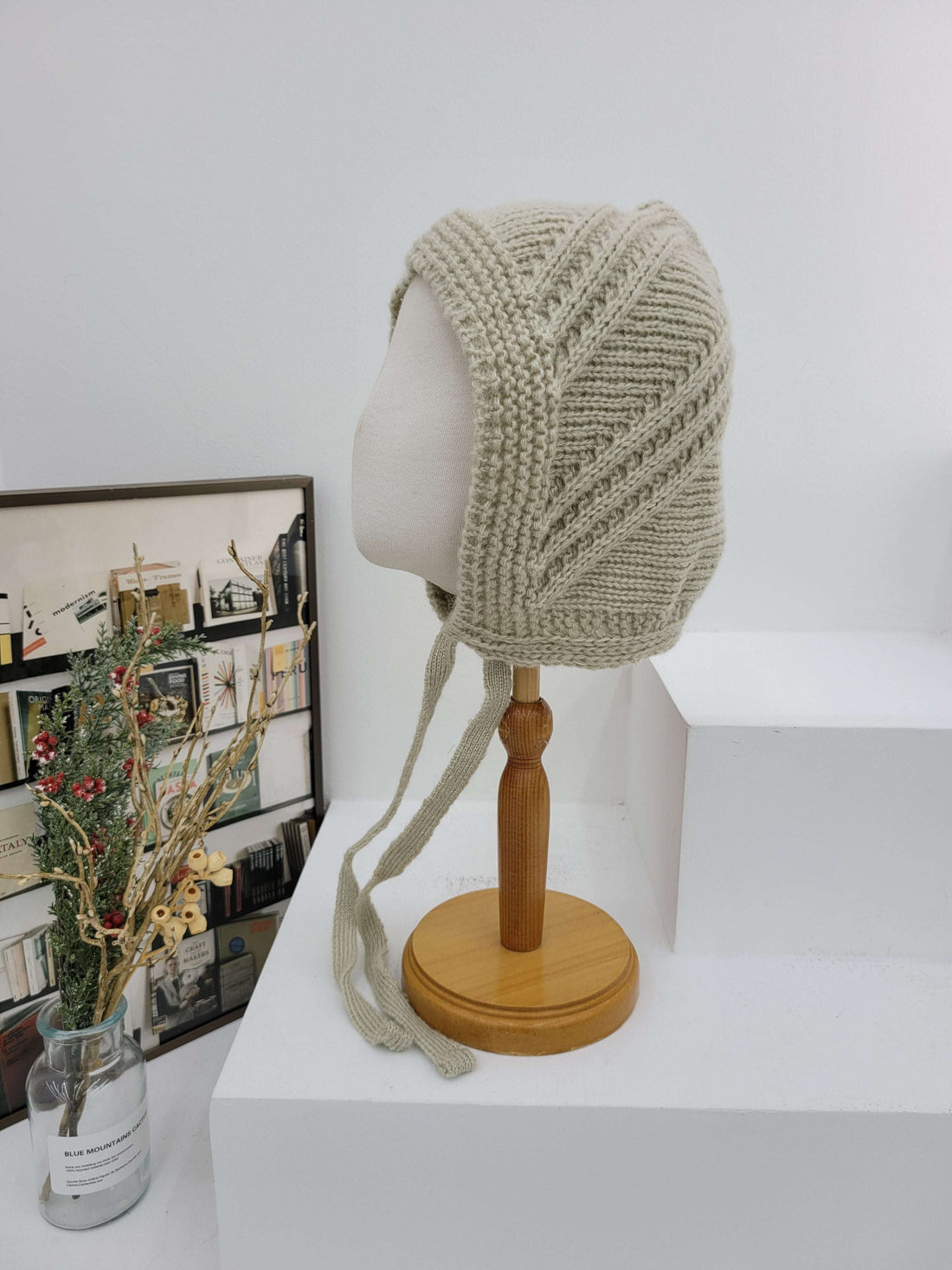 Knitted beige headband with wooden holder on a white wall