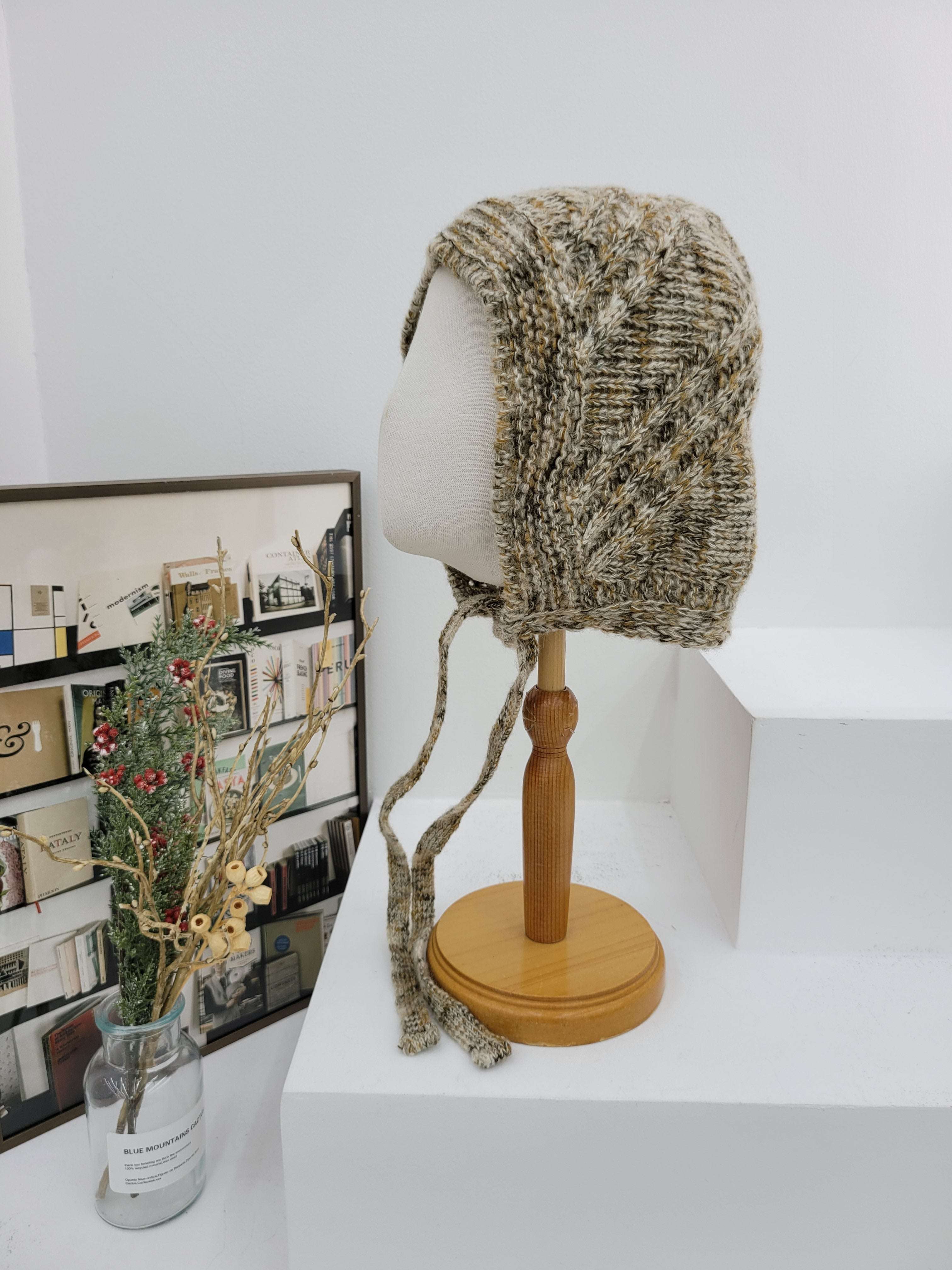 Knitted headband on a lampshade with a magazine underneath on a white surface
