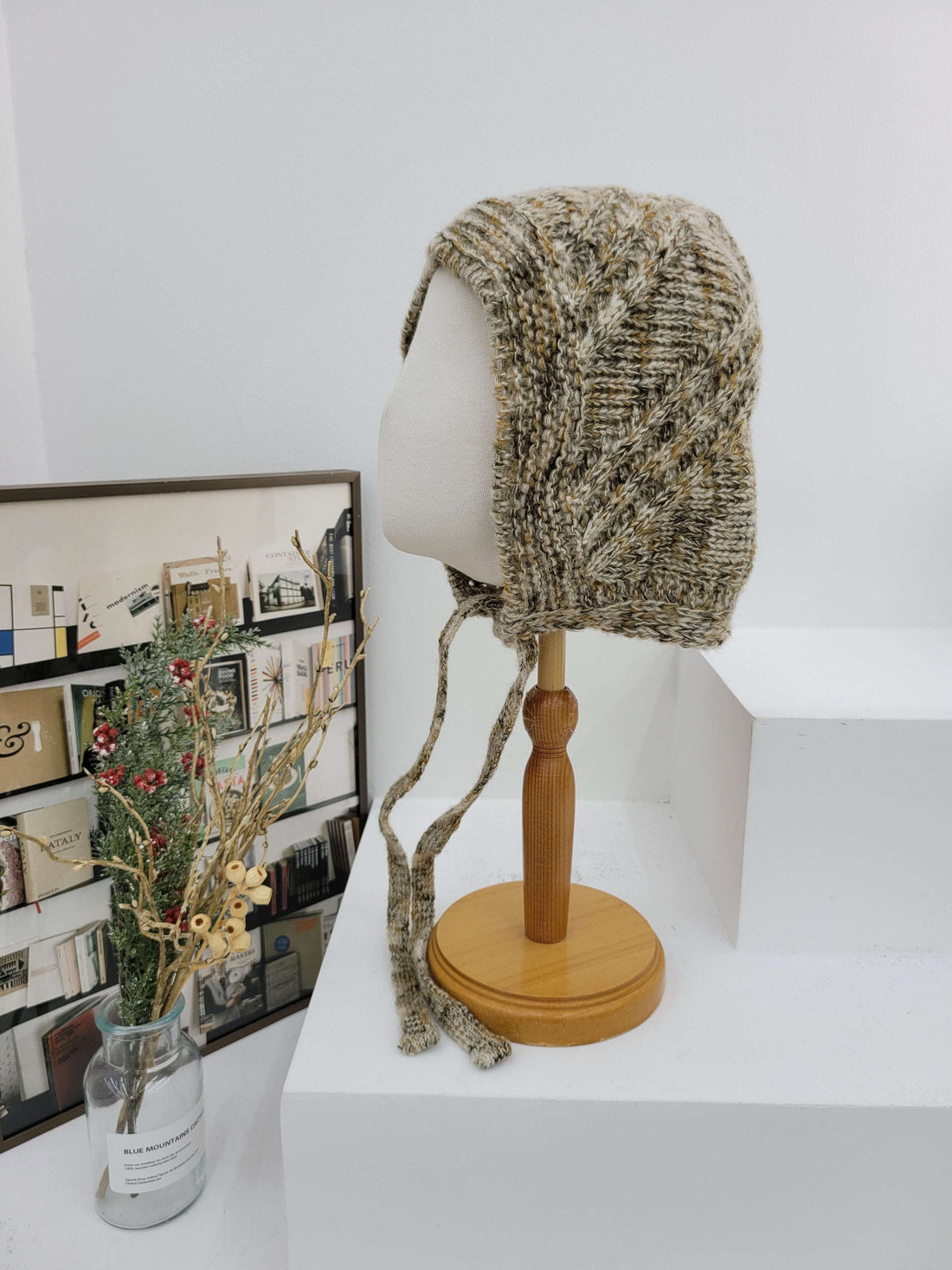 Knitted headband on a lampshade with a magazine underneath on a white surface