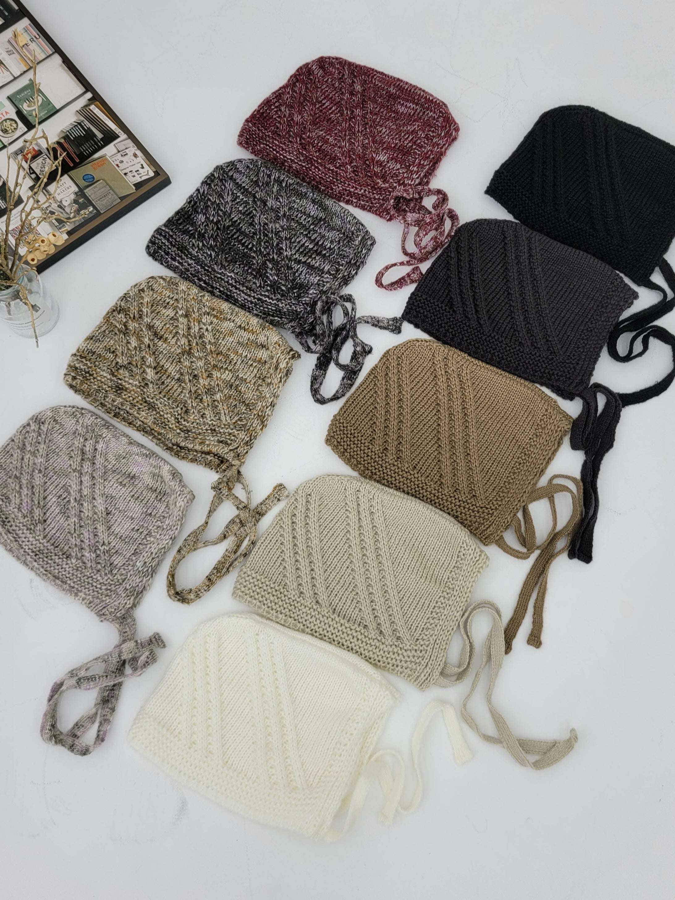 Collection of knitted hats in various colors on a white surface.