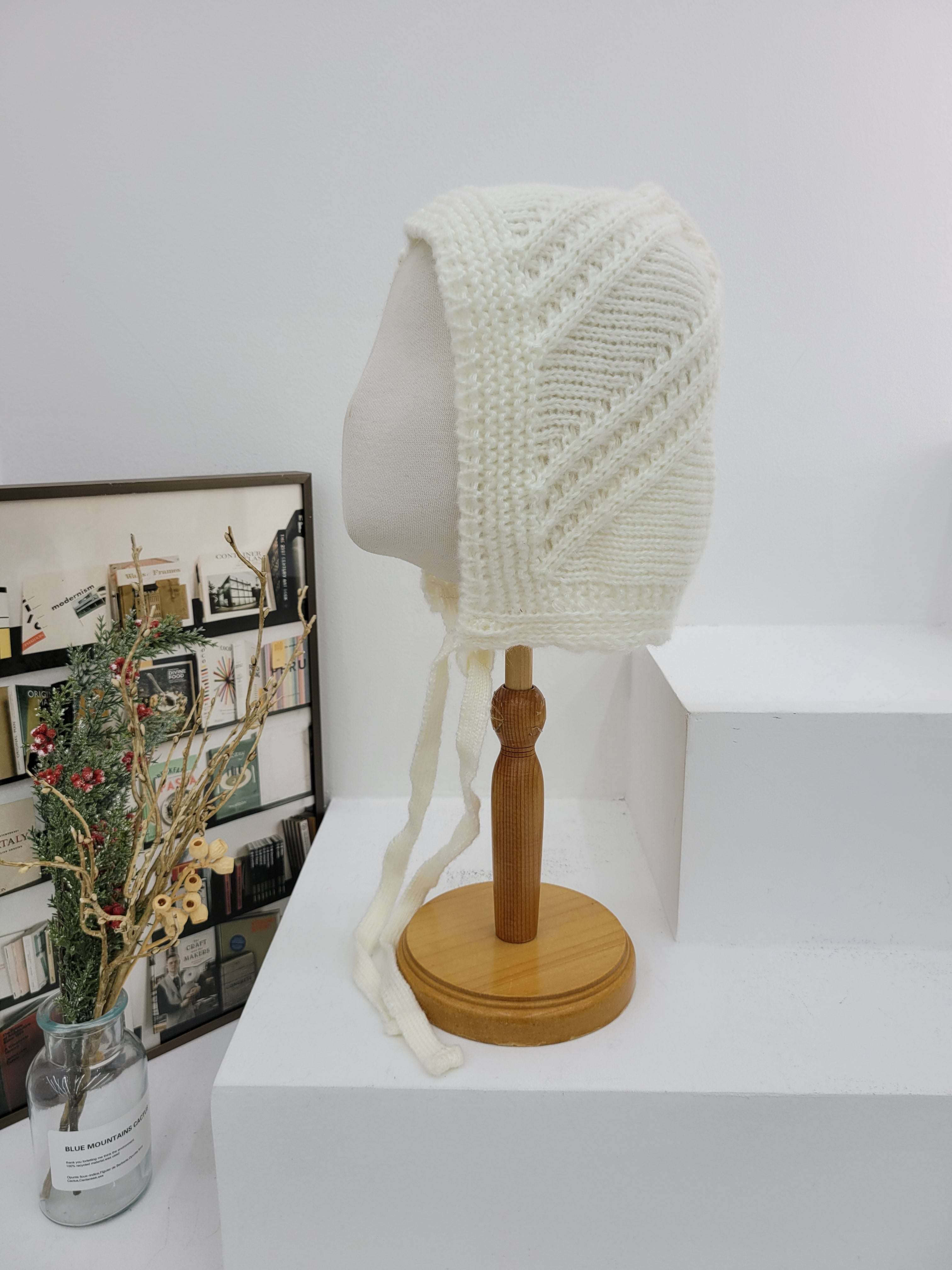 Decorative wall lamp with a textured white shade and wooden base on a white wall.