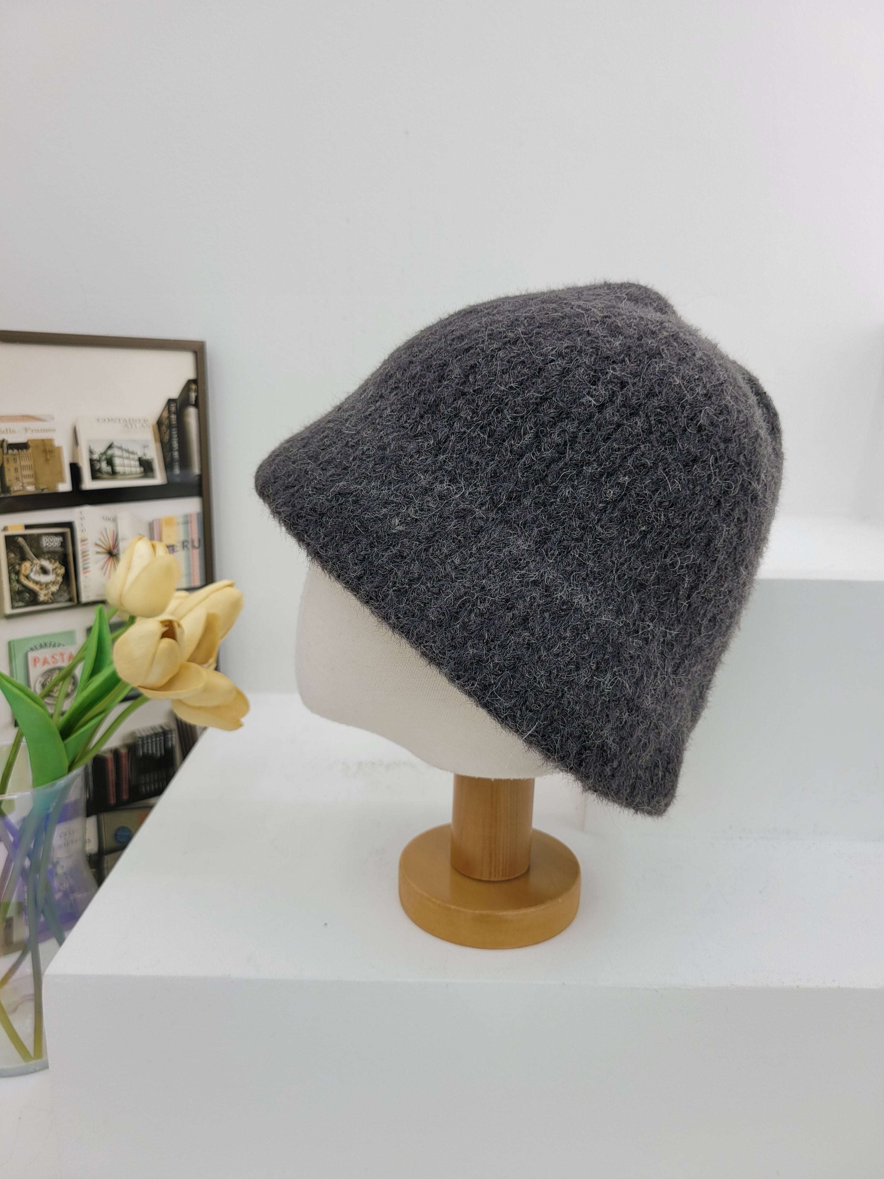 Gray beanie on a wooden hook with a magazine and flowers below