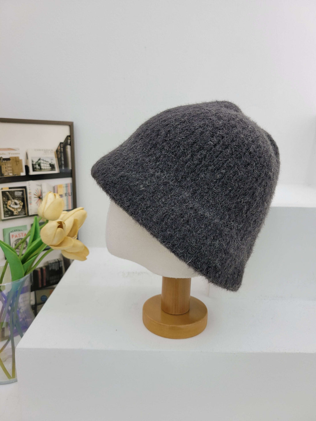 Gray beanie on a wooden hook with a magazine and flowers below