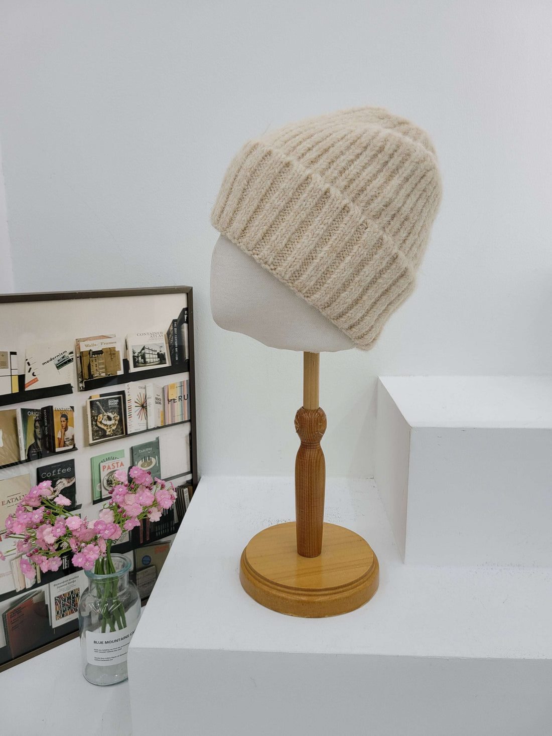 Wall-mounted lamp with a textured beige shade and wooden arm on a white wall.