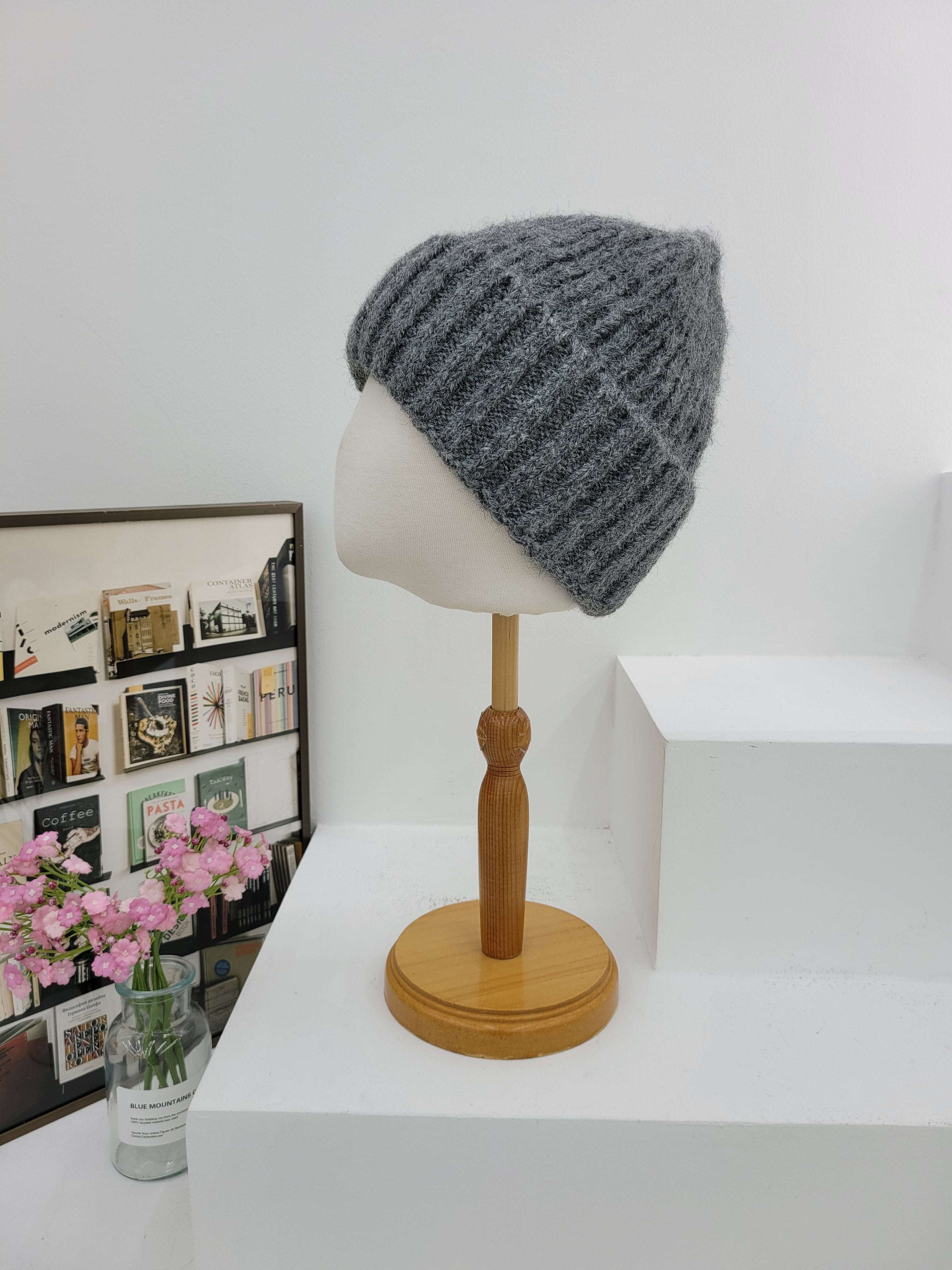 Gray knit beanie on a mannequin head with a wooden lamp in the background