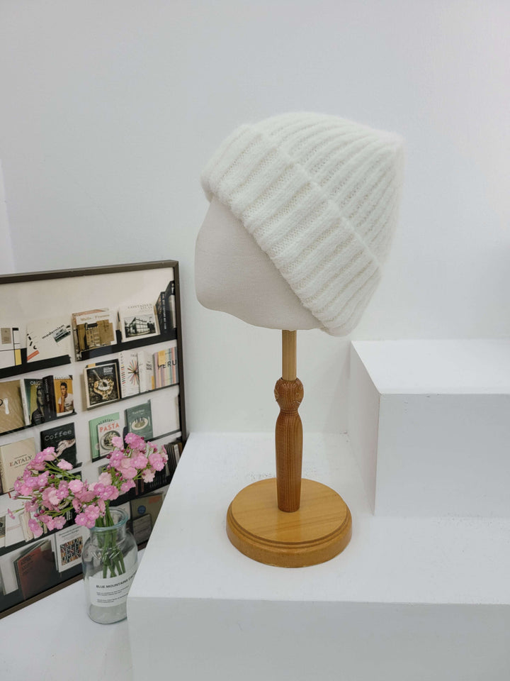 Wall-mounted lamp with wooden arm and white shade on a white wall.