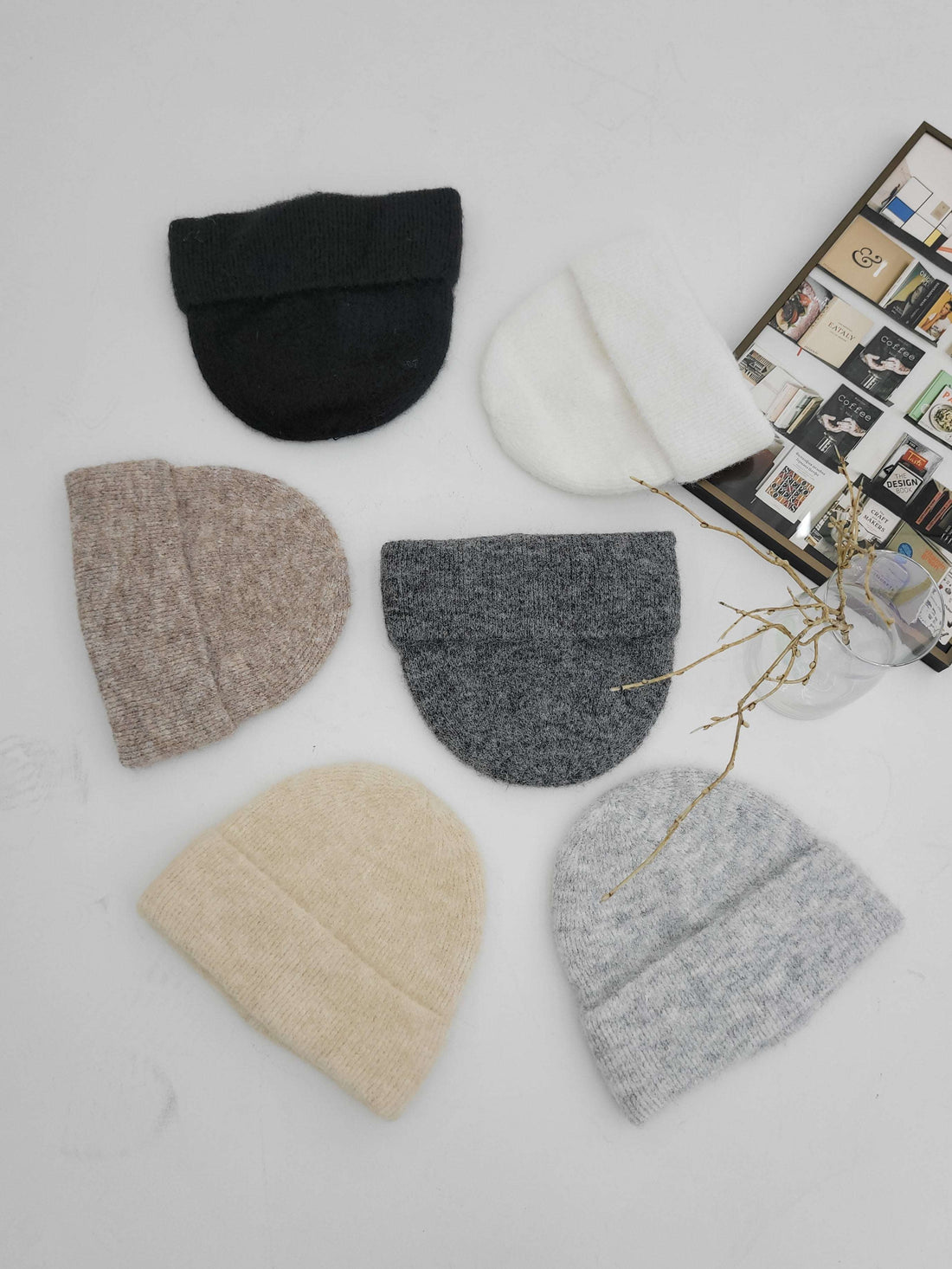 Set of six knit hats in various colors on a light surface.