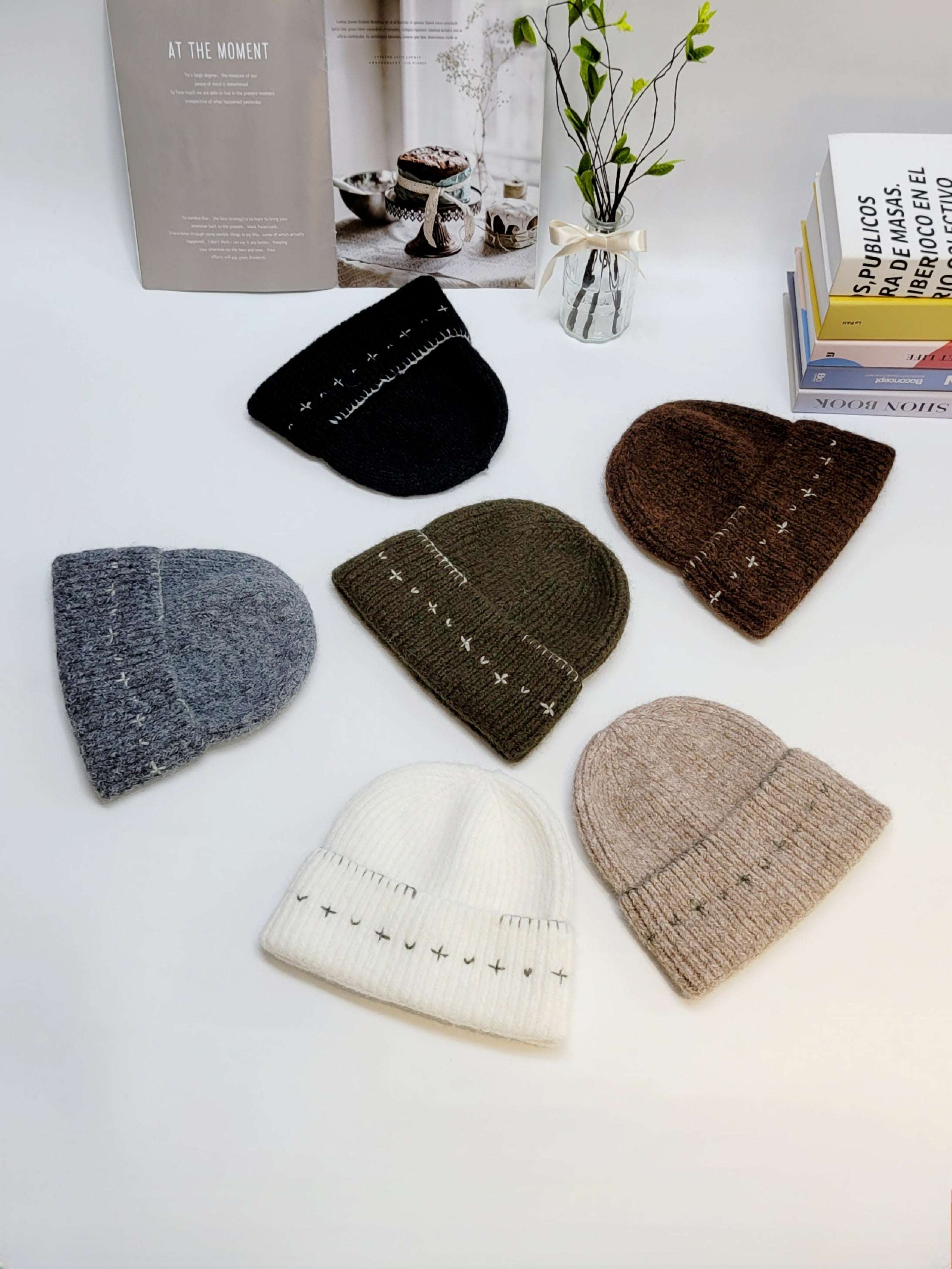 Set of six knit hats in various colors on a white surface.