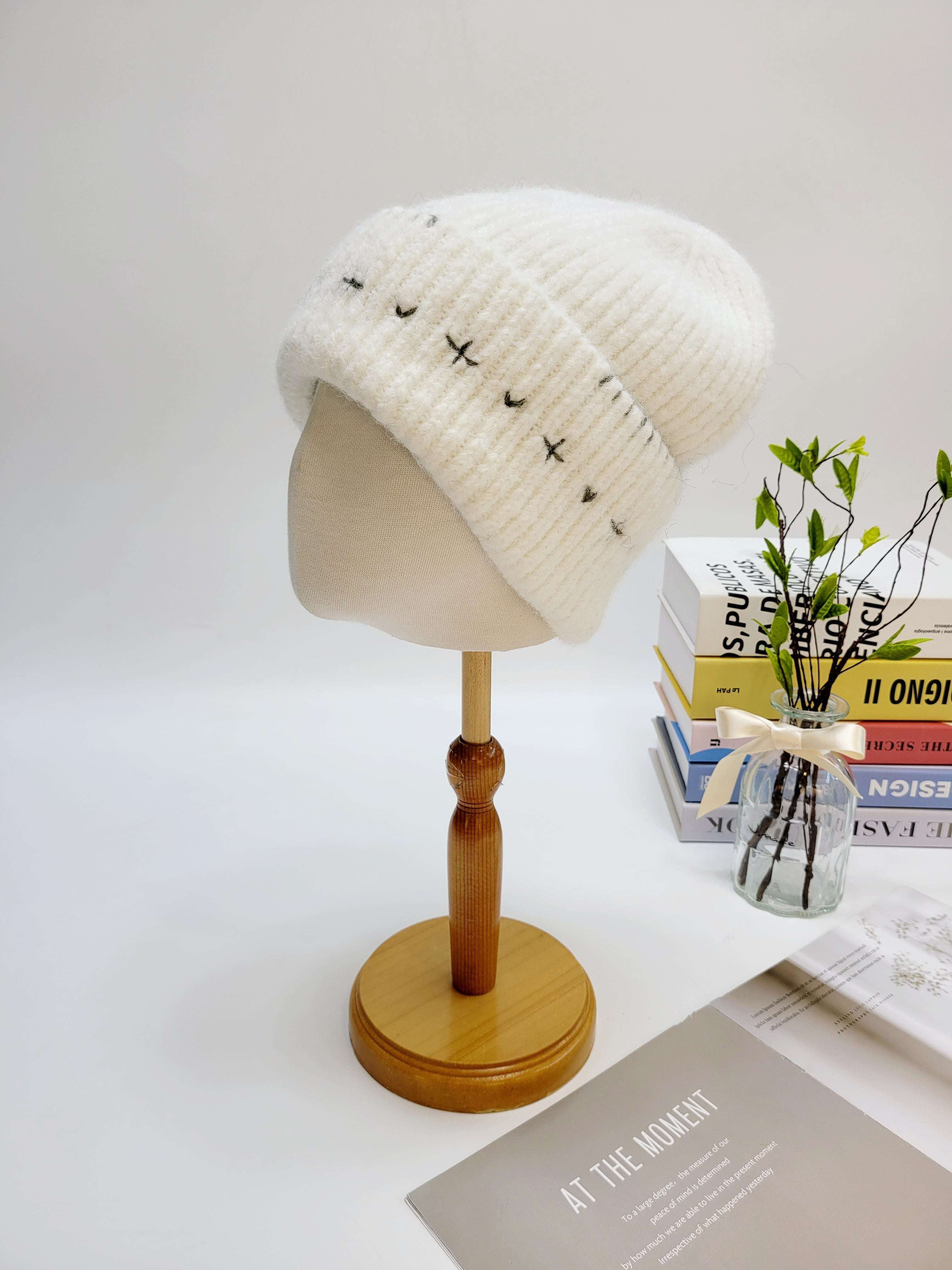 White knitted beanie on a wooden mannequin head with a white background