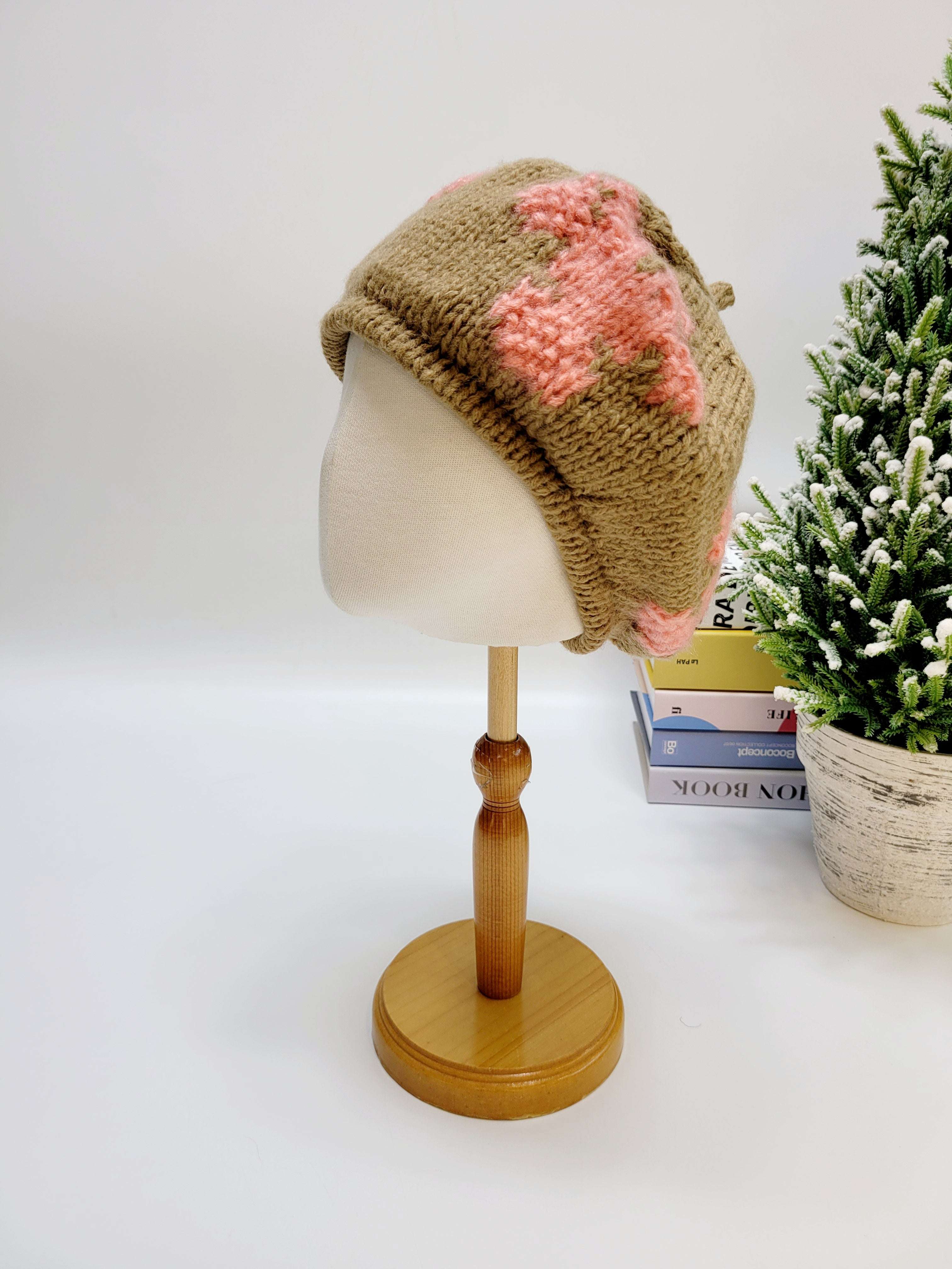 Knitted hat with pink flower on a mannequin head against a white background