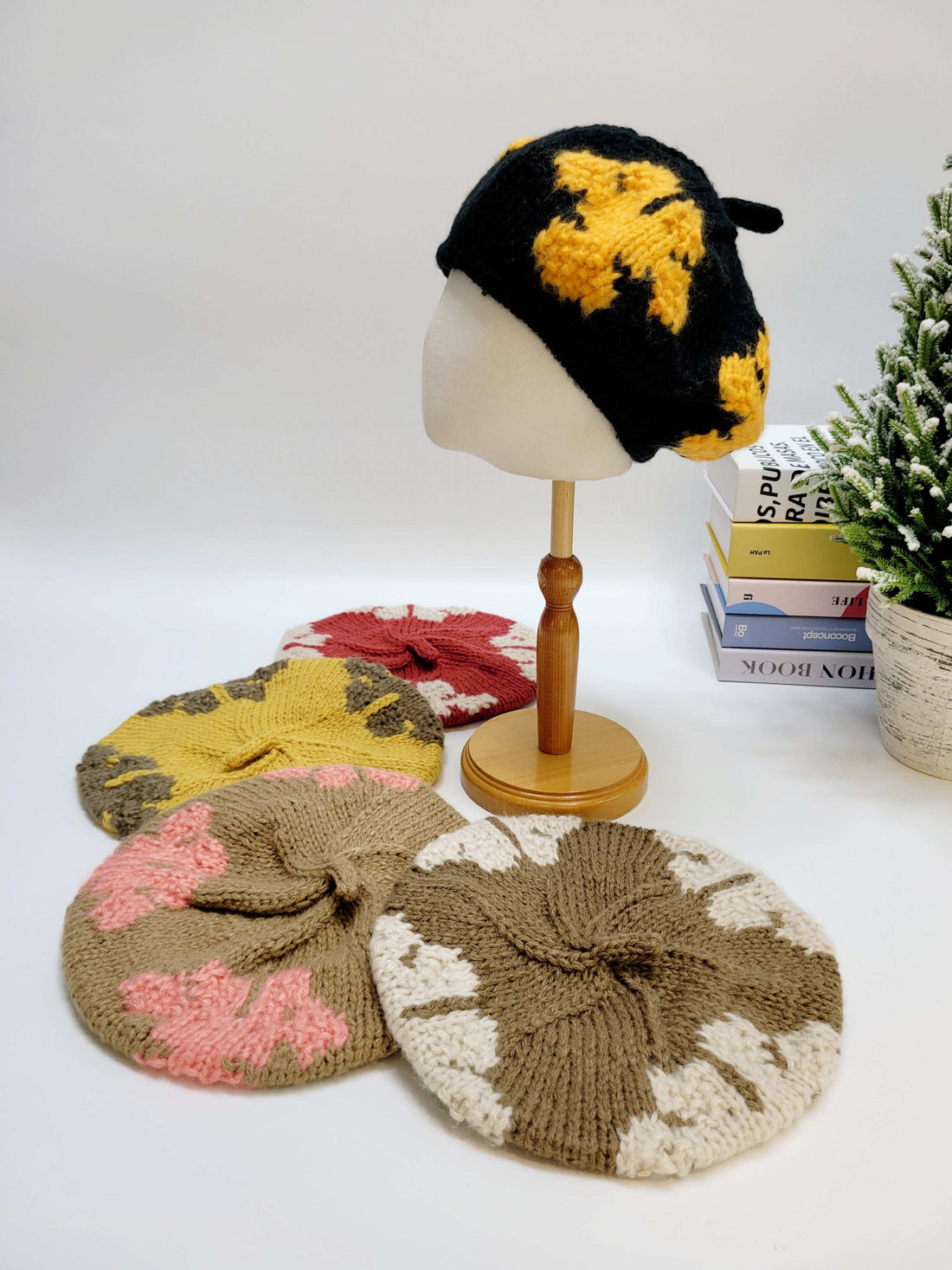 Collection of knitted hats on a white surface with a plant in the background
