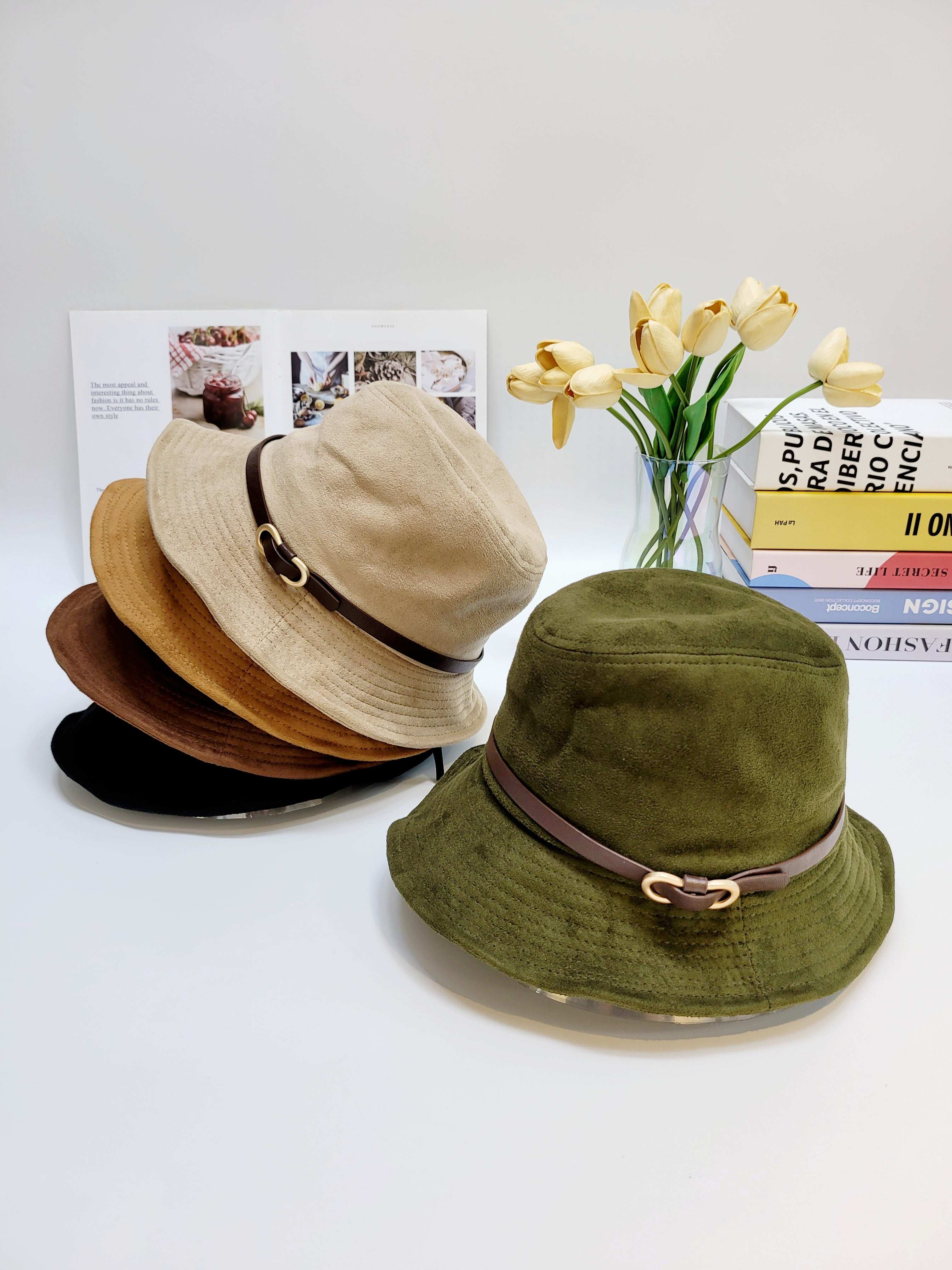 Three bucket hats in beige, brown, and green with brown straps on a white surface.
