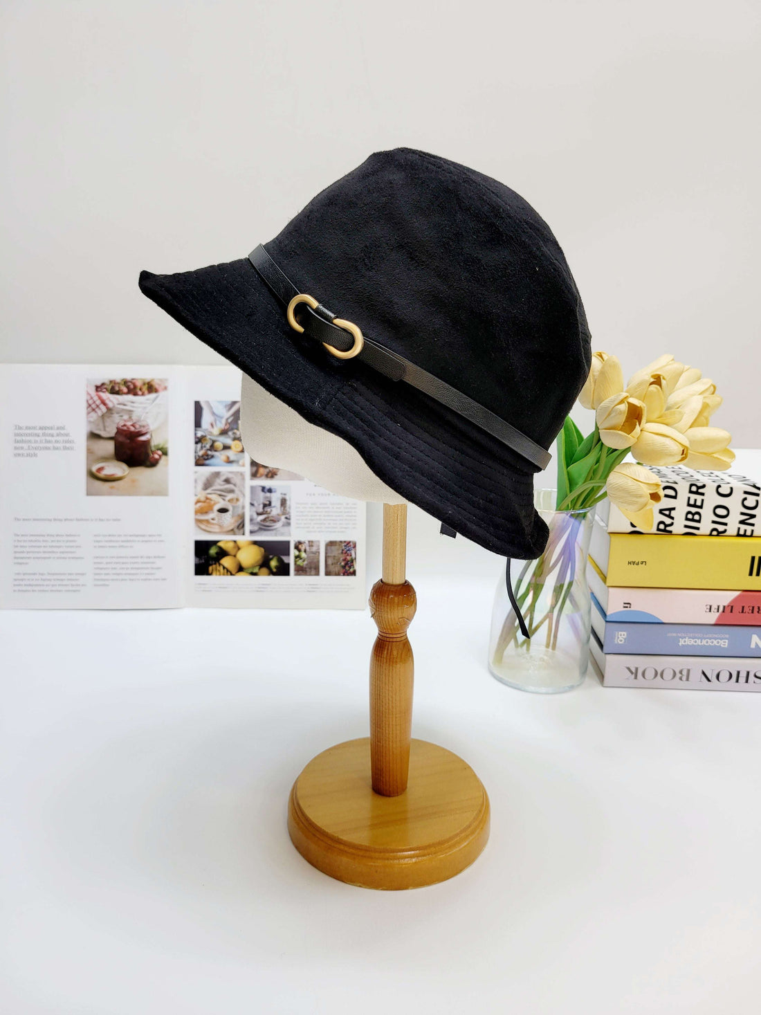 Black bucket hat on a wooden stand with a white background
