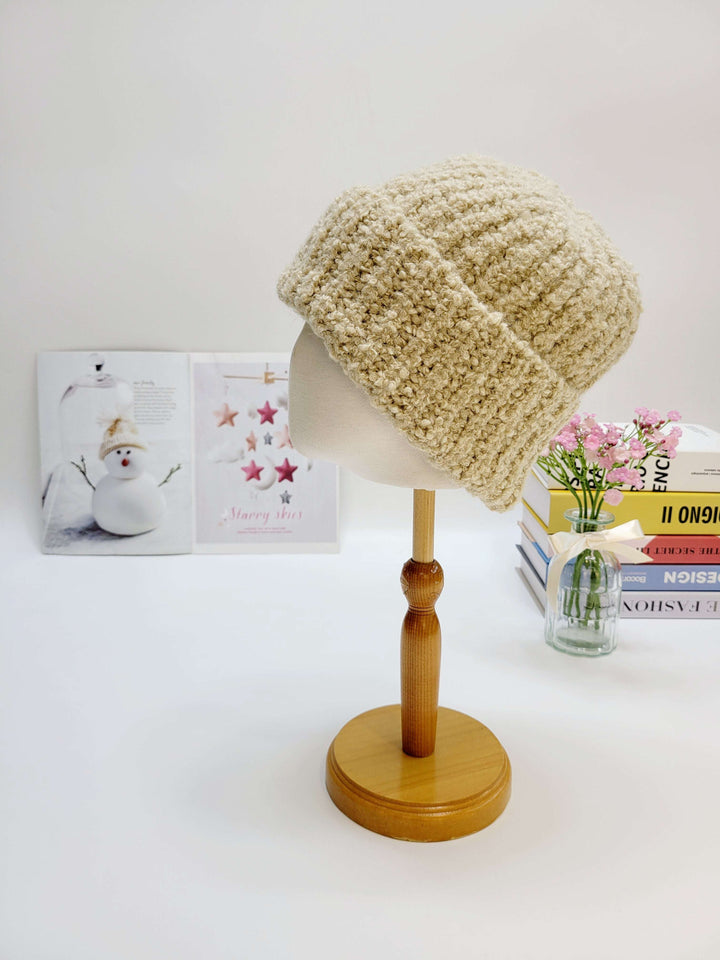 Beige knitted hat on a wooden mannequin head with a white background