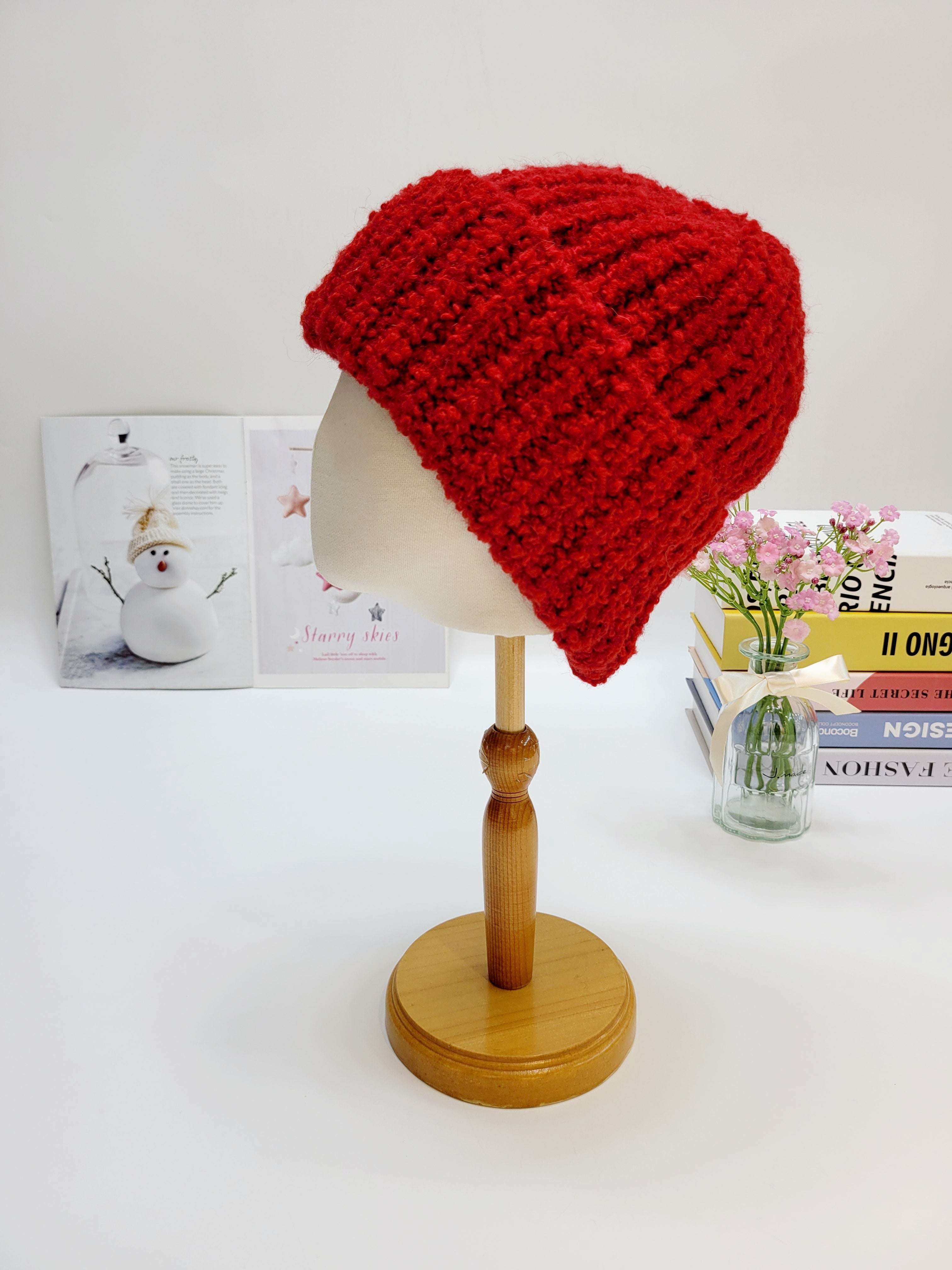 Red knitted beanie on a mannequin head against a light background