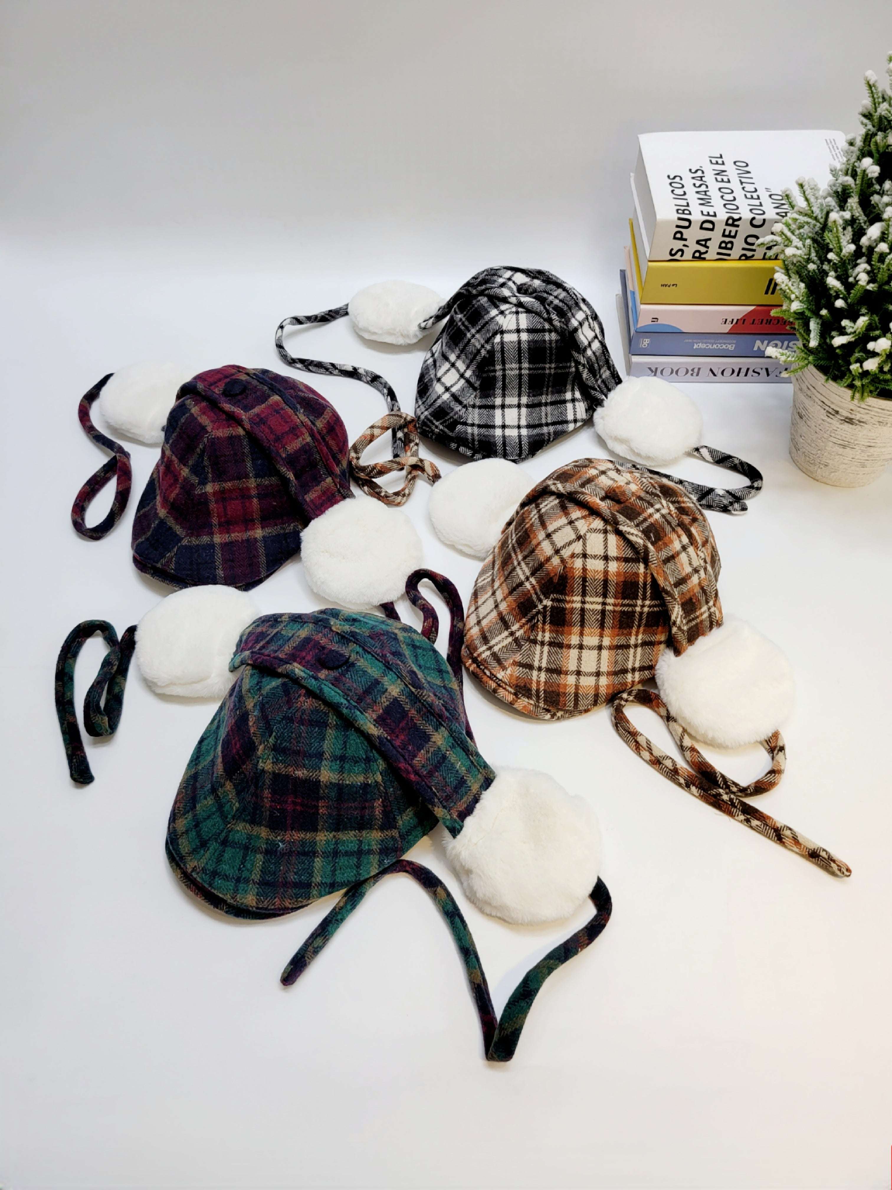 Plaid hats with pom-poms on a white surface