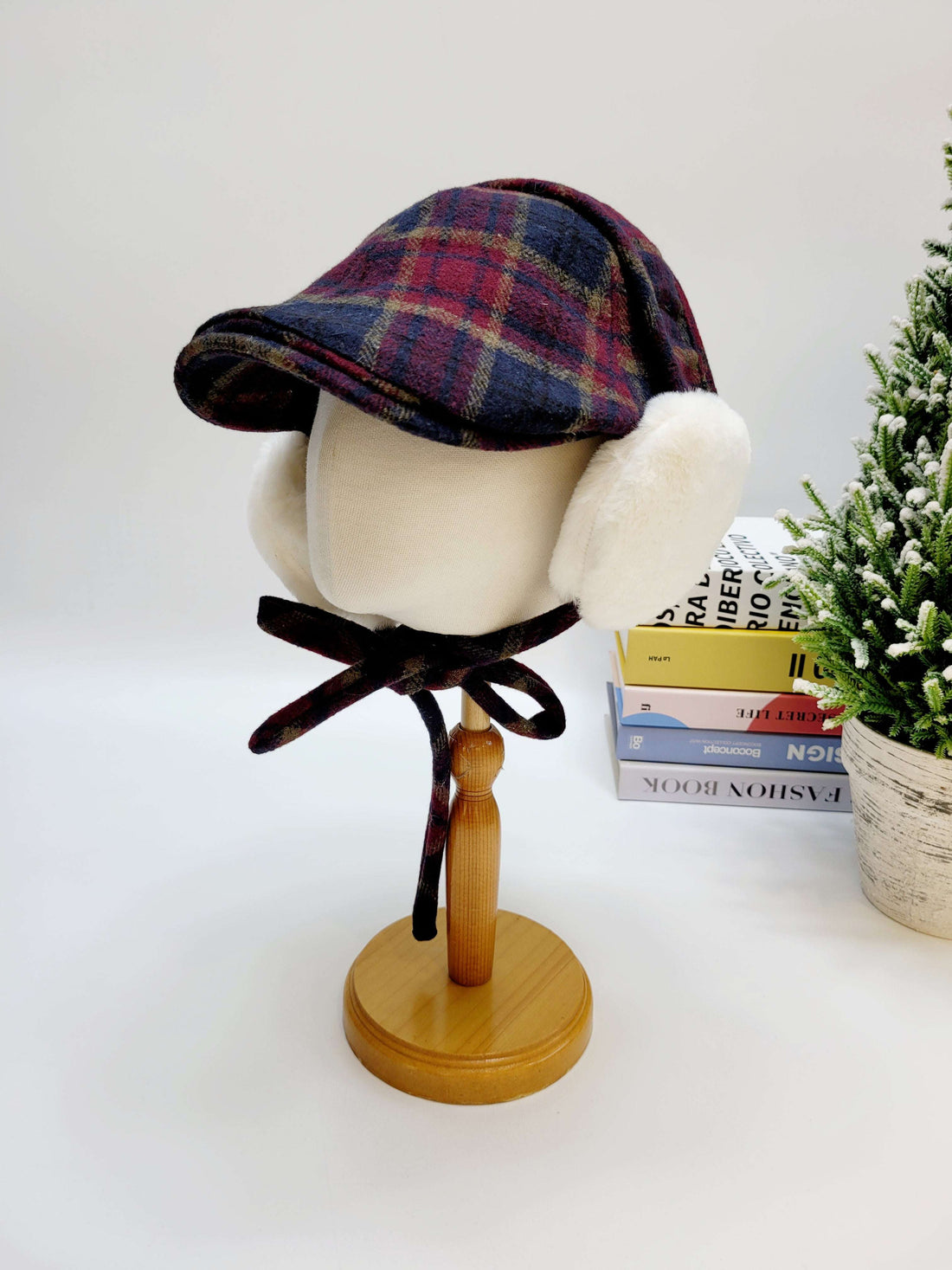 Plaid hat with fur trim on a wooden stand against a white background