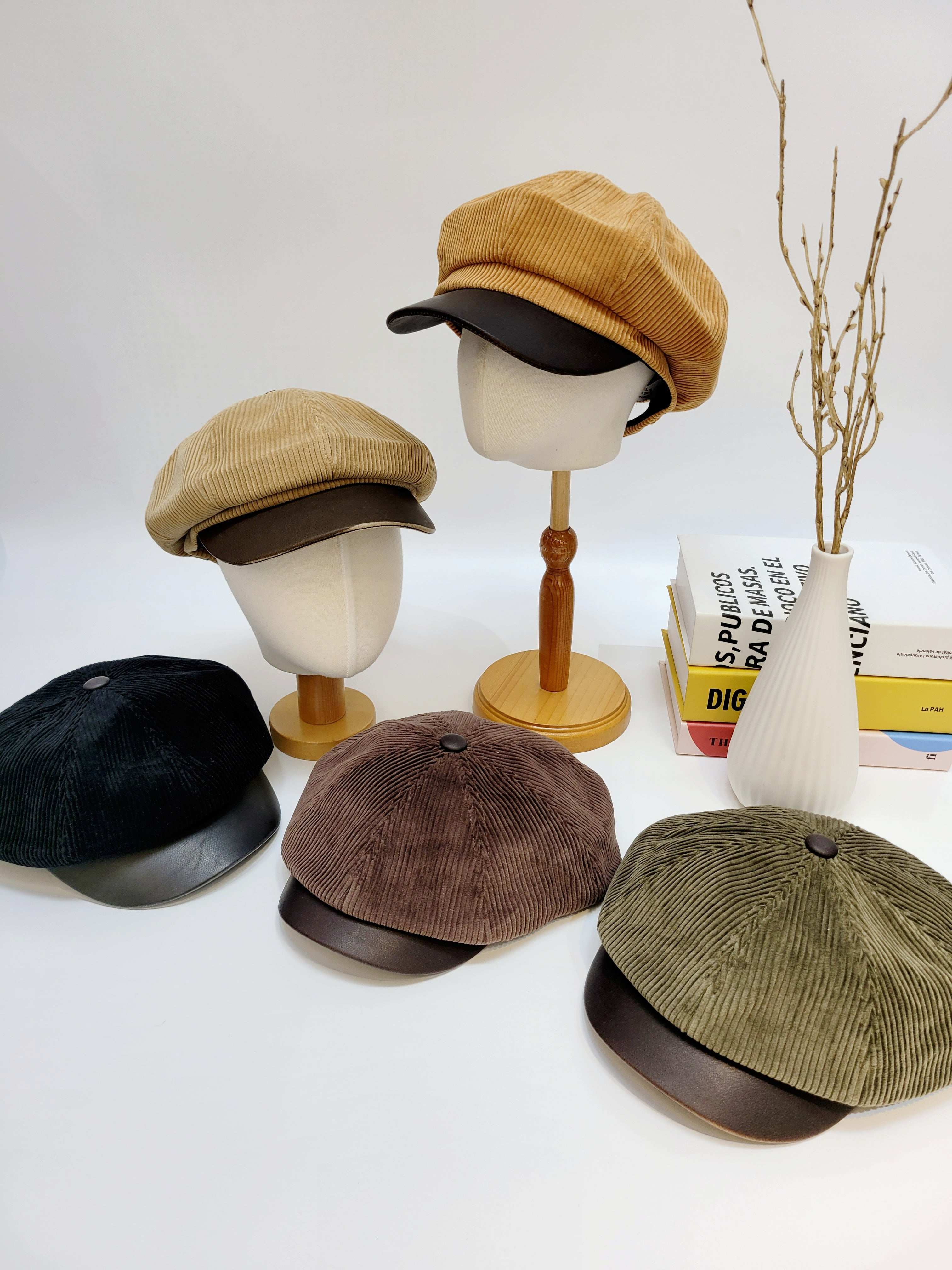 Collection of corduroy caps on mannequin heads with a minimal background