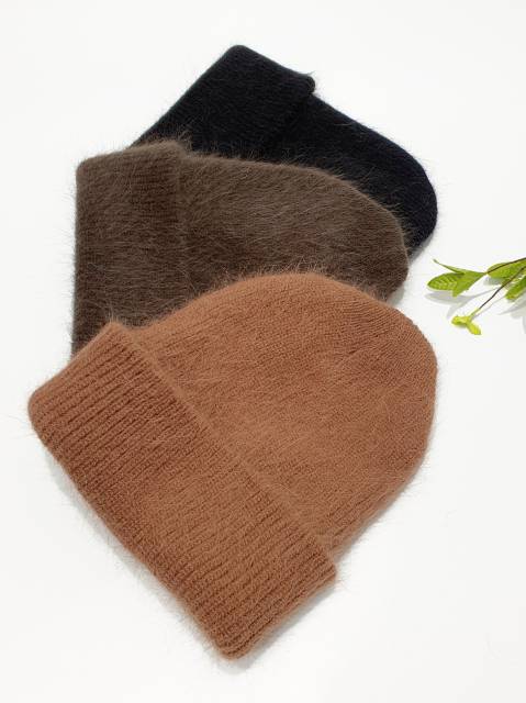 Three knit hats in black, brown, and beige on a white background with a small green plant.