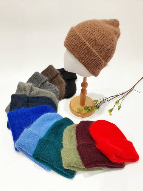 Collection of colourful beanies on a mannequin head with a white background