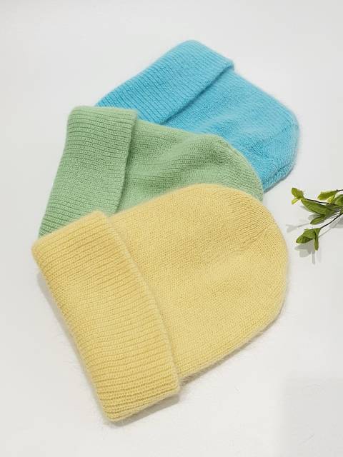 Three knit beanies in blue, green, and yellow on a white background.