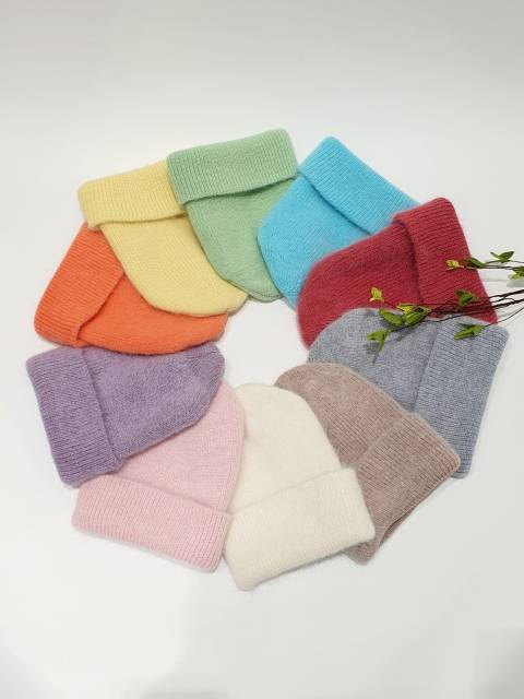 Colorful knit beanies arranged in a circle on a white background