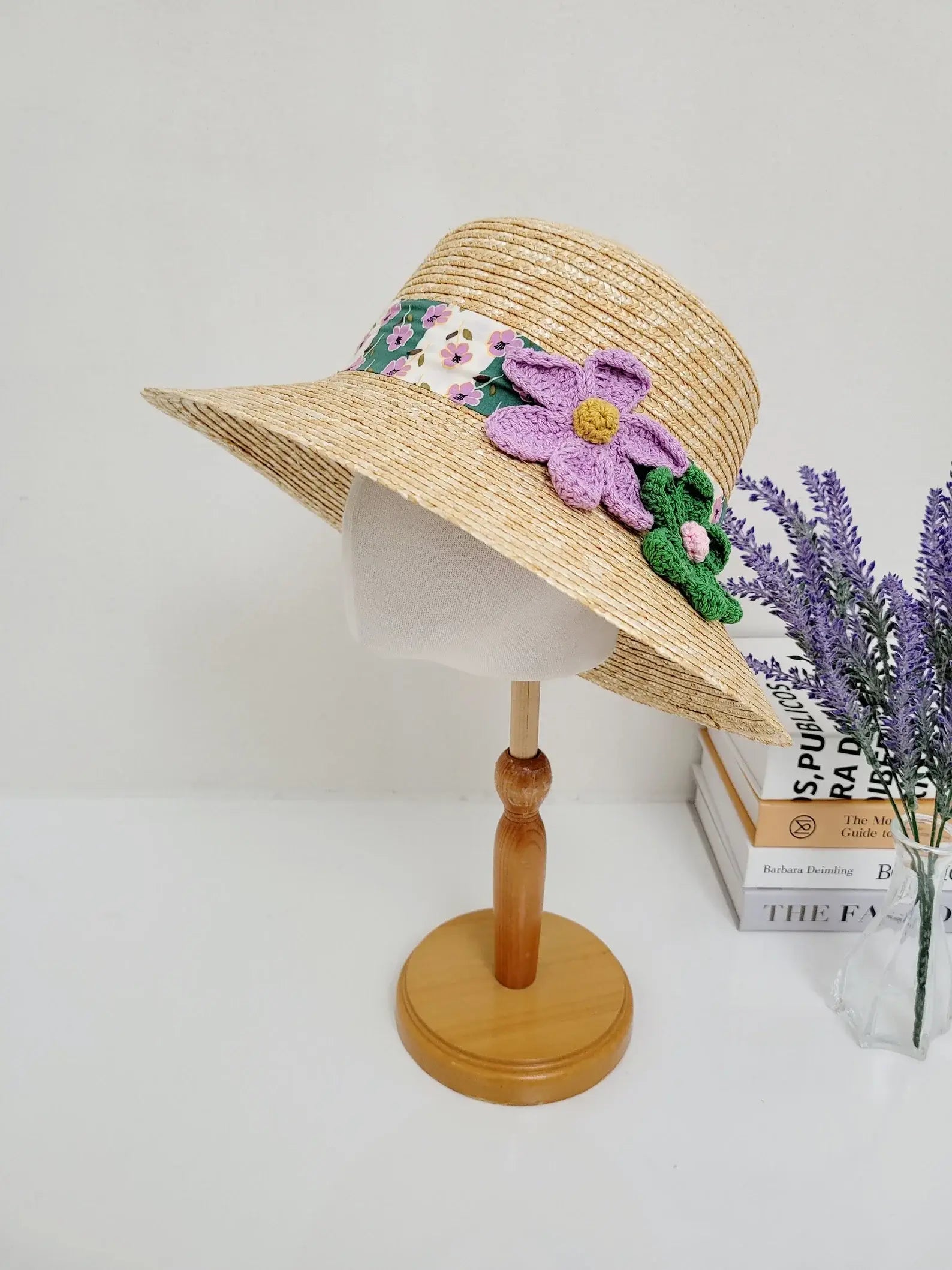 daisy - straw bucket hat: Natural straw hat with a floral print band, adorned with a purple crochet flower and green leaves.
