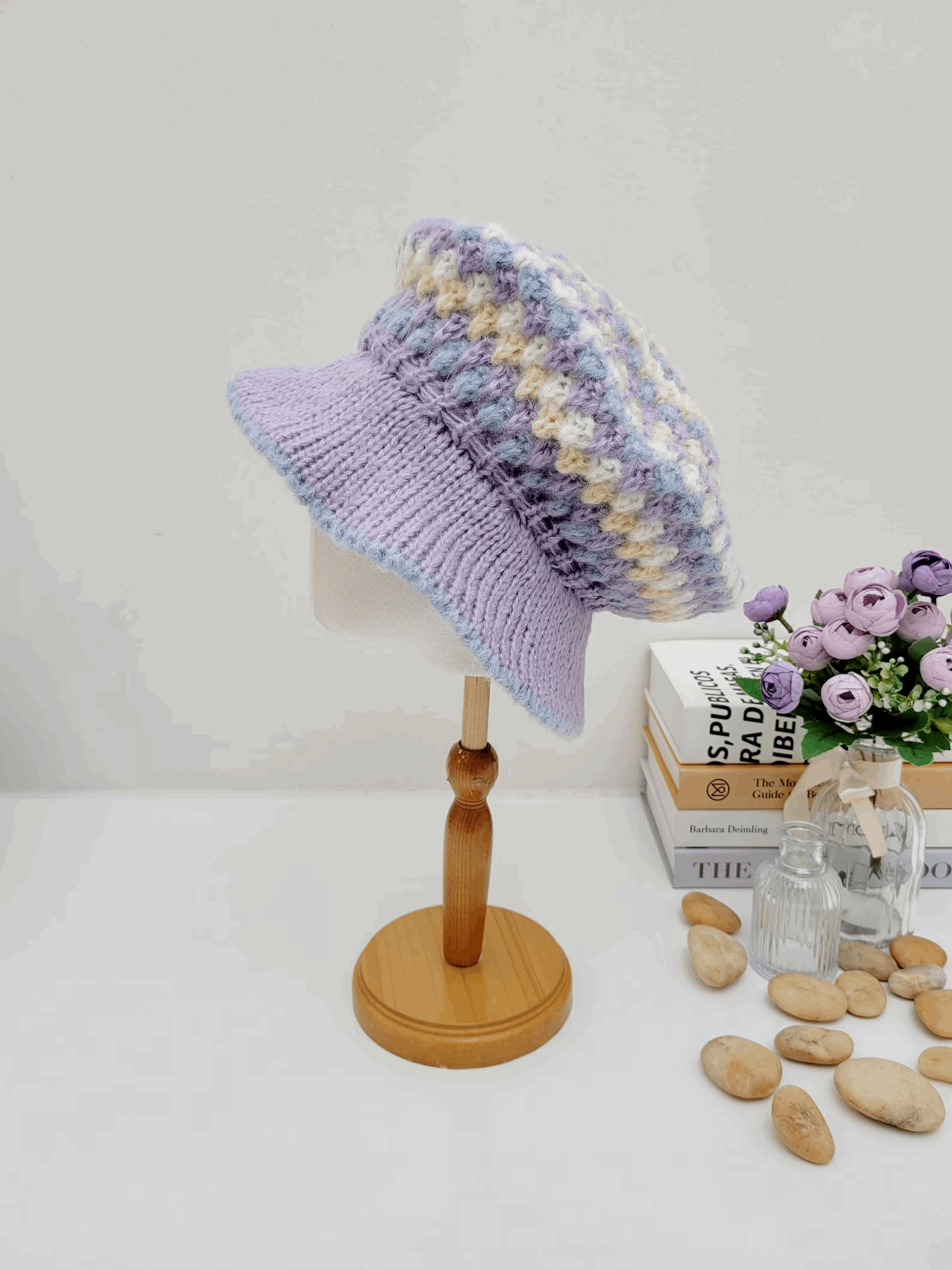 A collection of crocheted beret hats in various colors displayed on a wooden stand and table.