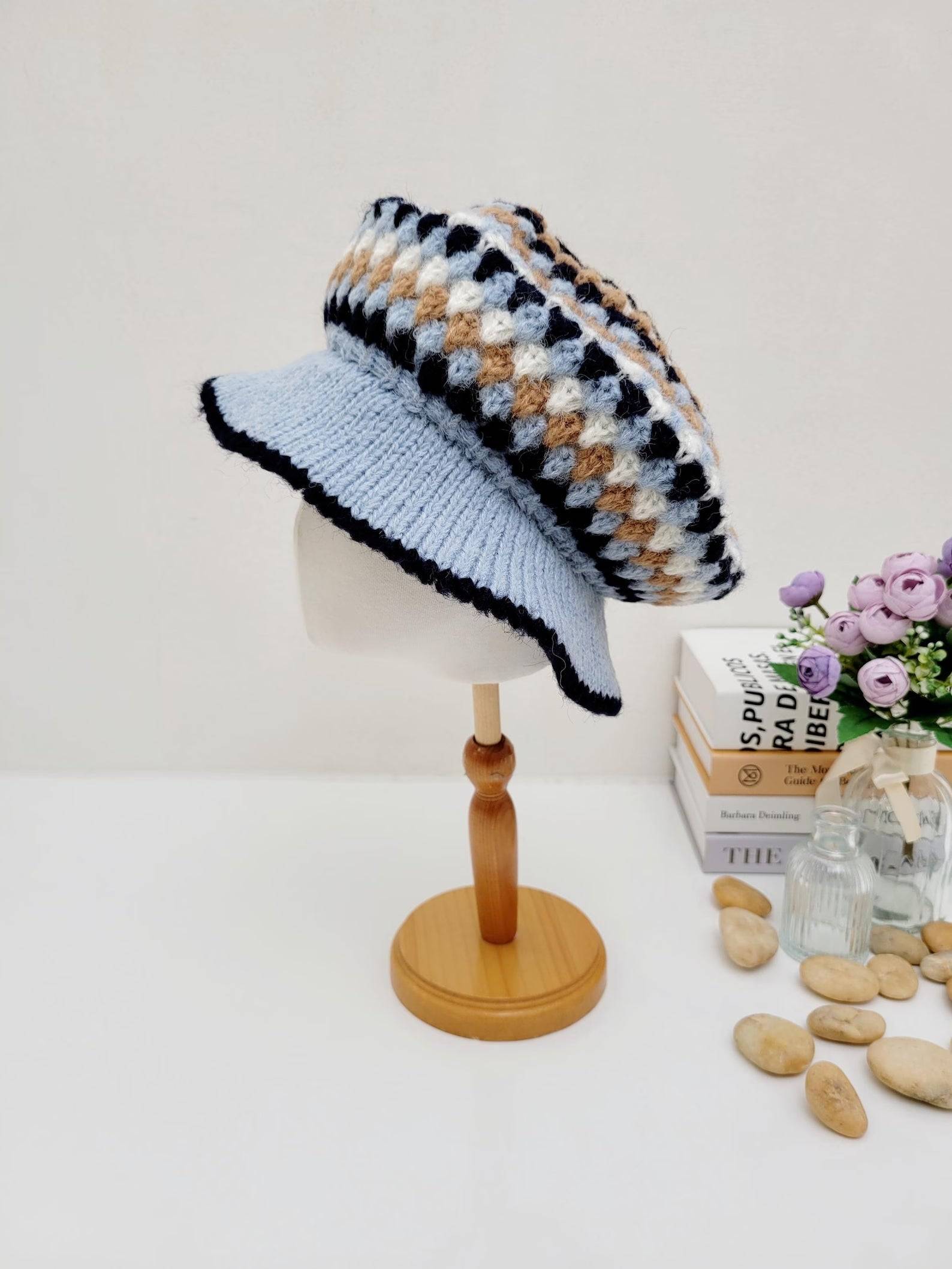 A collection of crocheted beret hats in various colors displayed on a wooden stand and table.