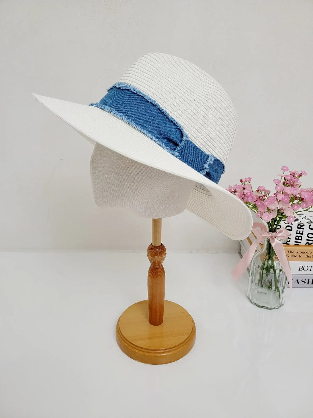 LONG ISLAND white sun hat with frayed denim band, offering stylish sun protection. Displayed on a wooden stand.